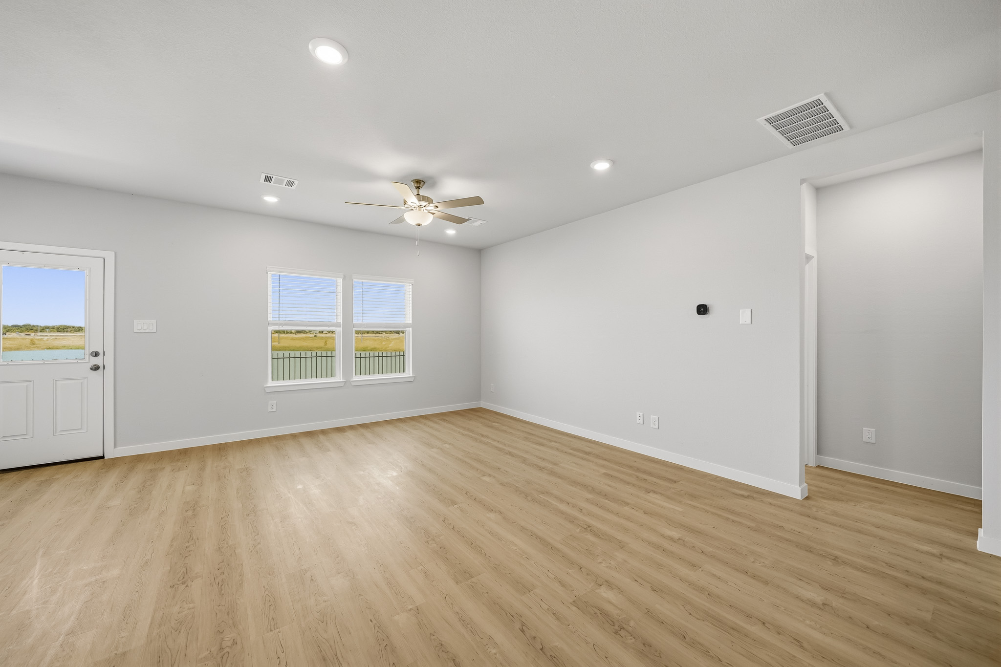 A room with a wood floor and a ceiling fan and a wood floor.