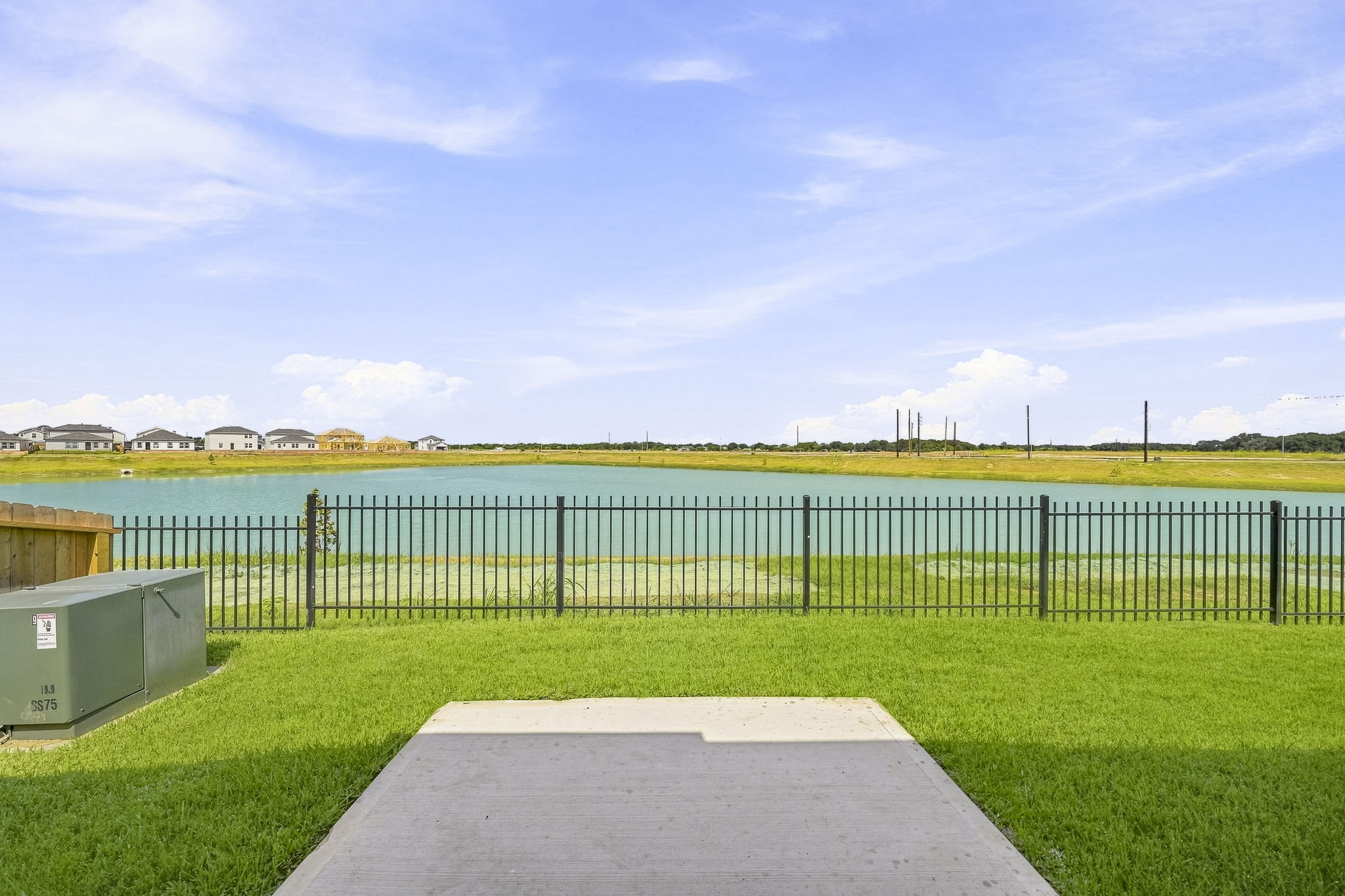A body of water with grass and a fence around it.