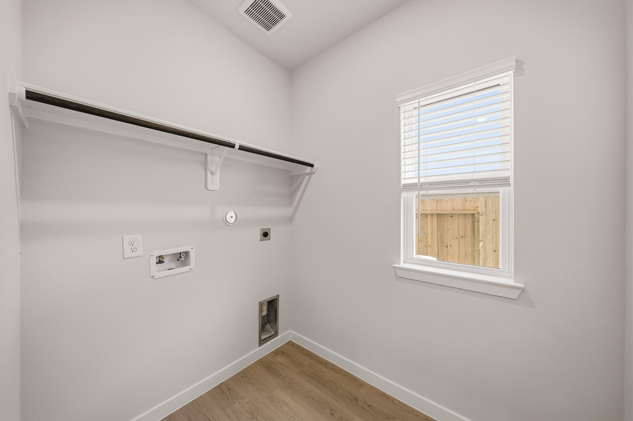 A room with a wood floor and a window with a light on the wall.