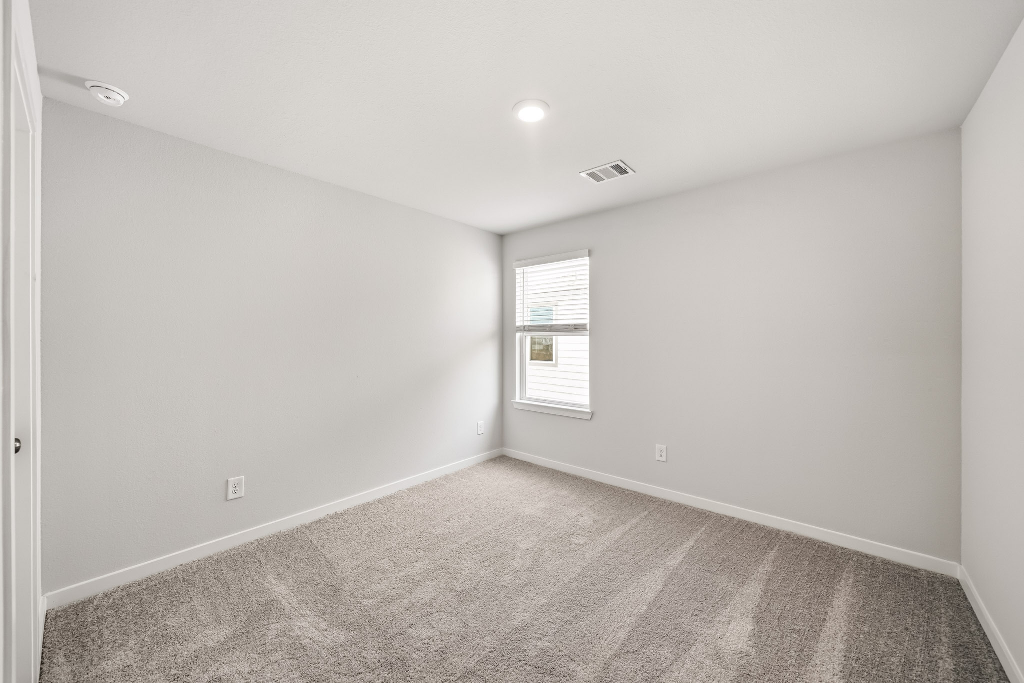 A room with a carpet and a window.