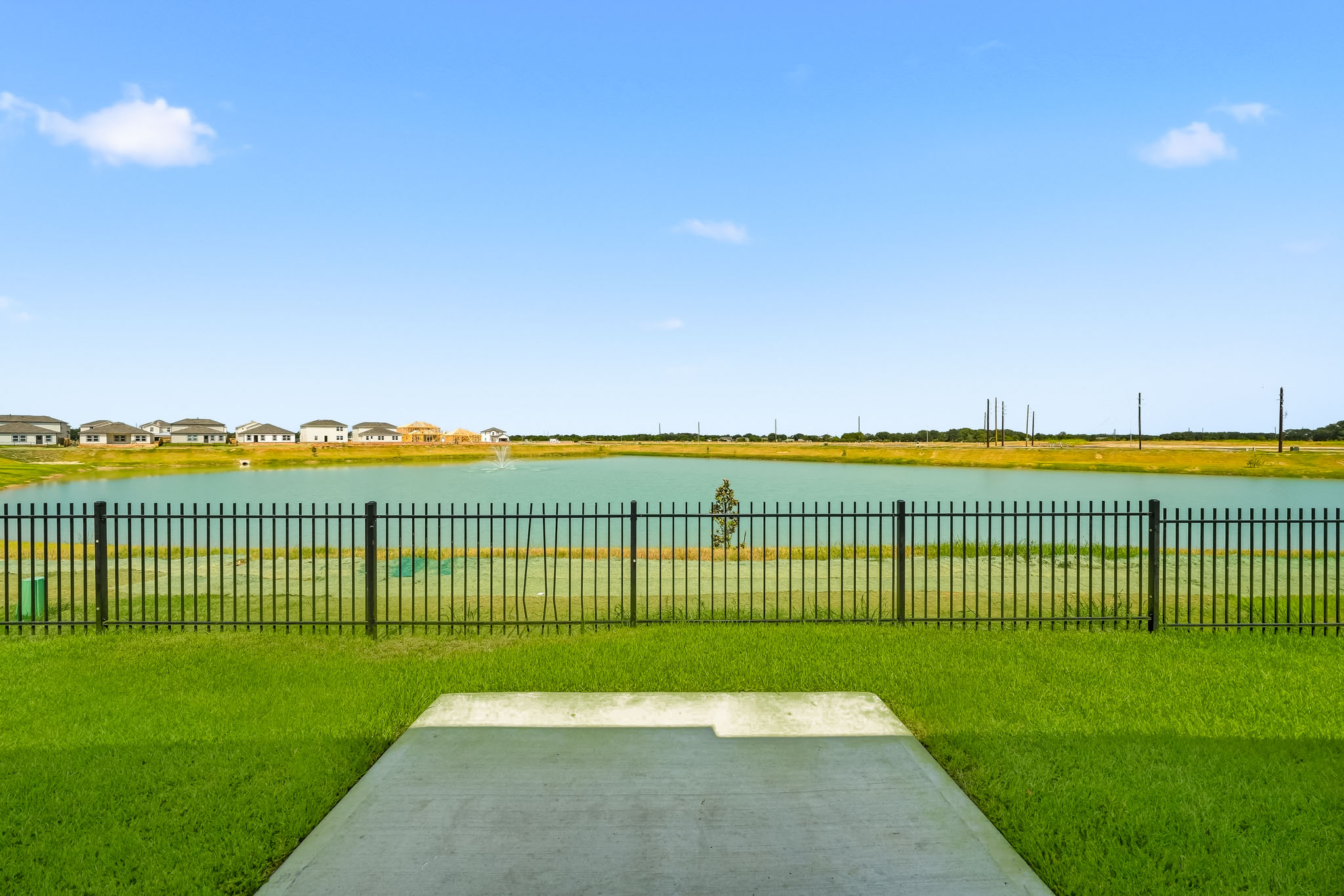 A body of water with grass and a fence around it.