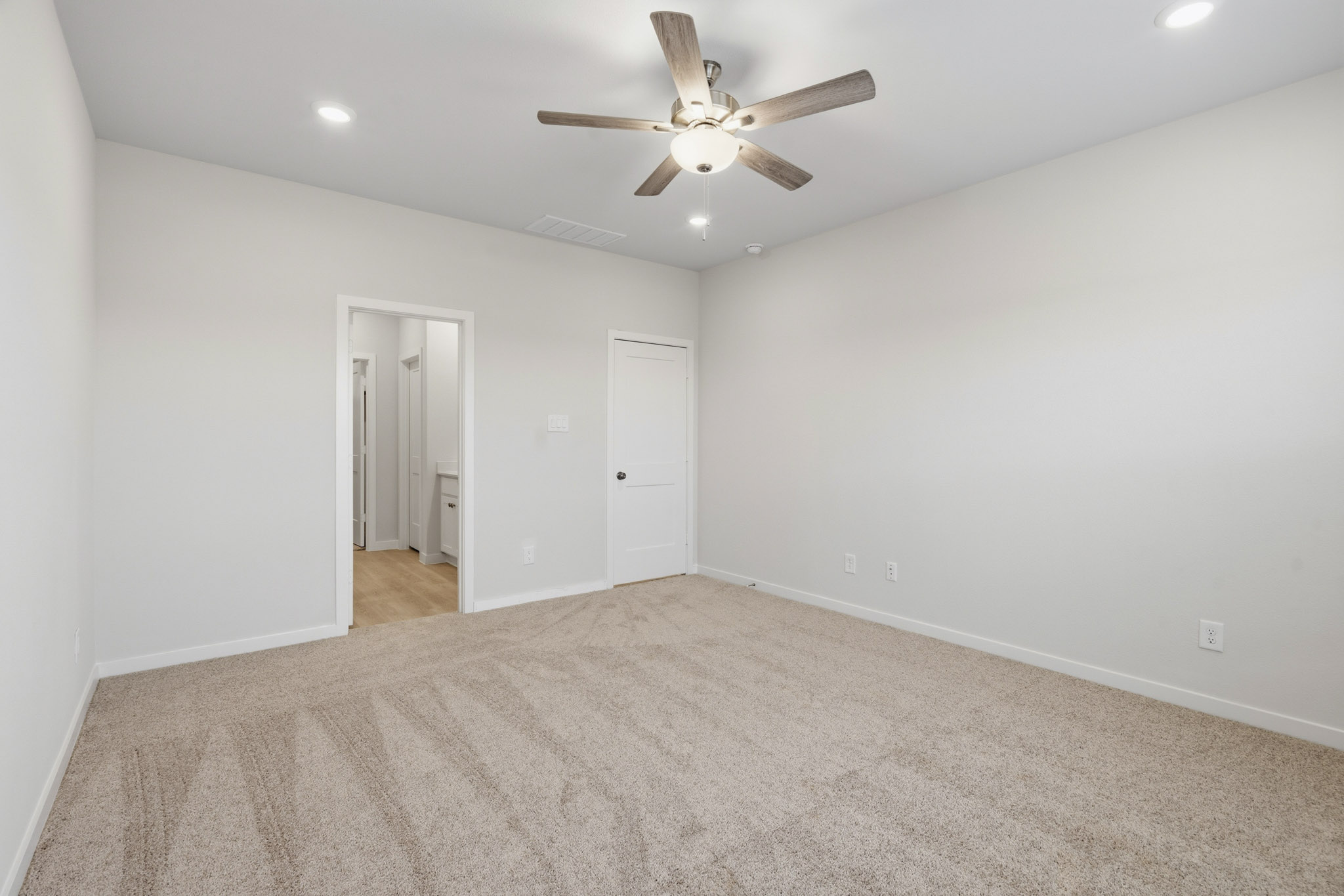 A room with a ceiling fan and a carpet.