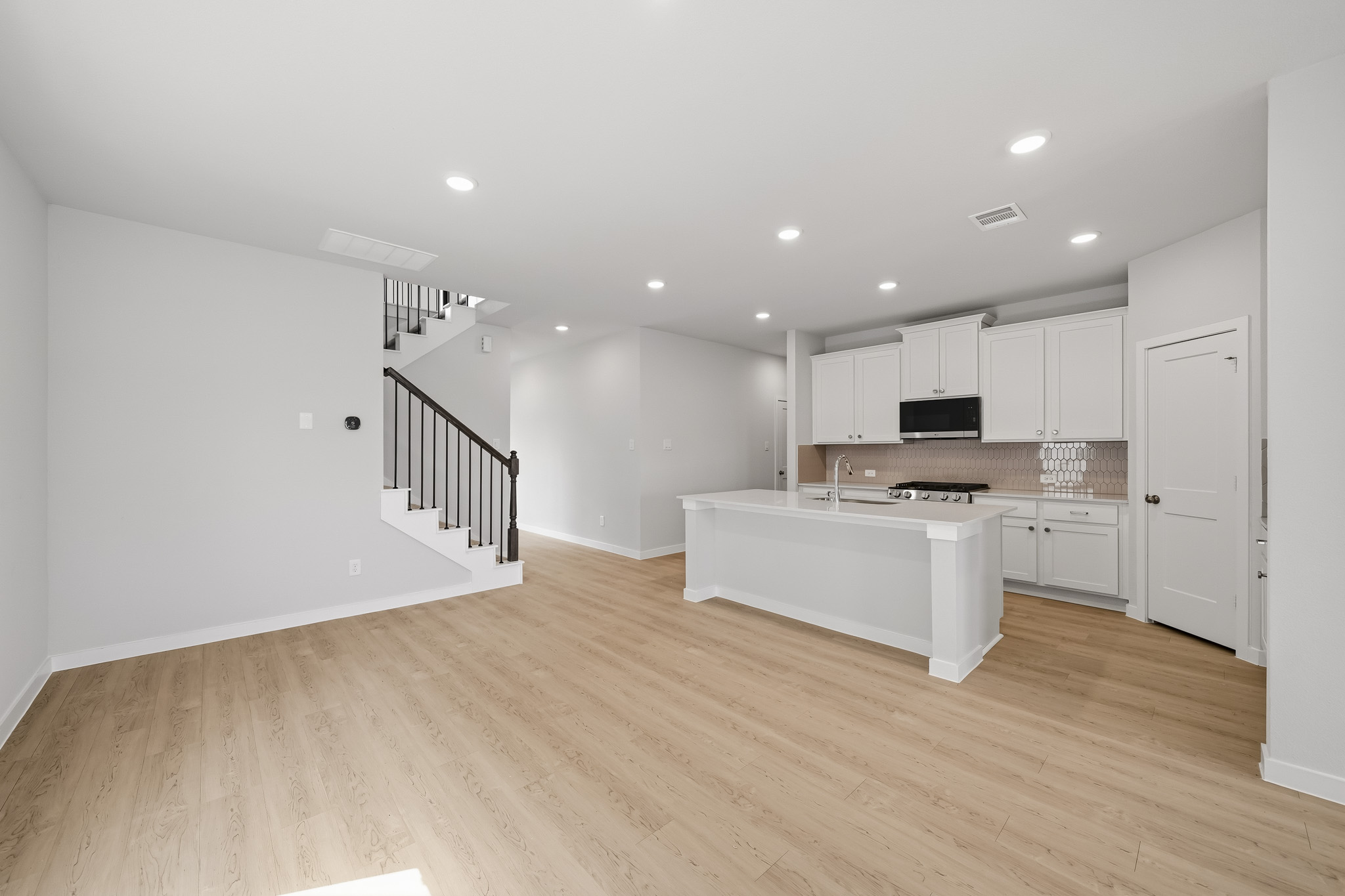 A large white kitchen with a wood floor.