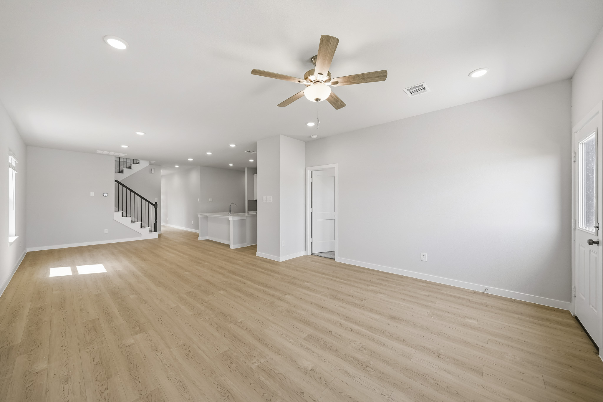 A large empty room with a ceiling fan and a wood floor.