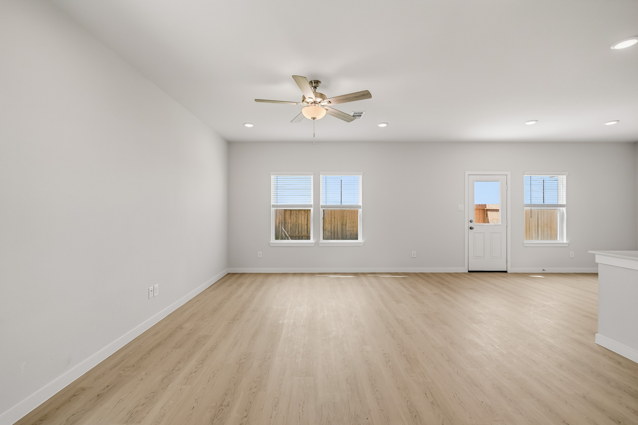 A room with a ceiling fan and a wood floor.