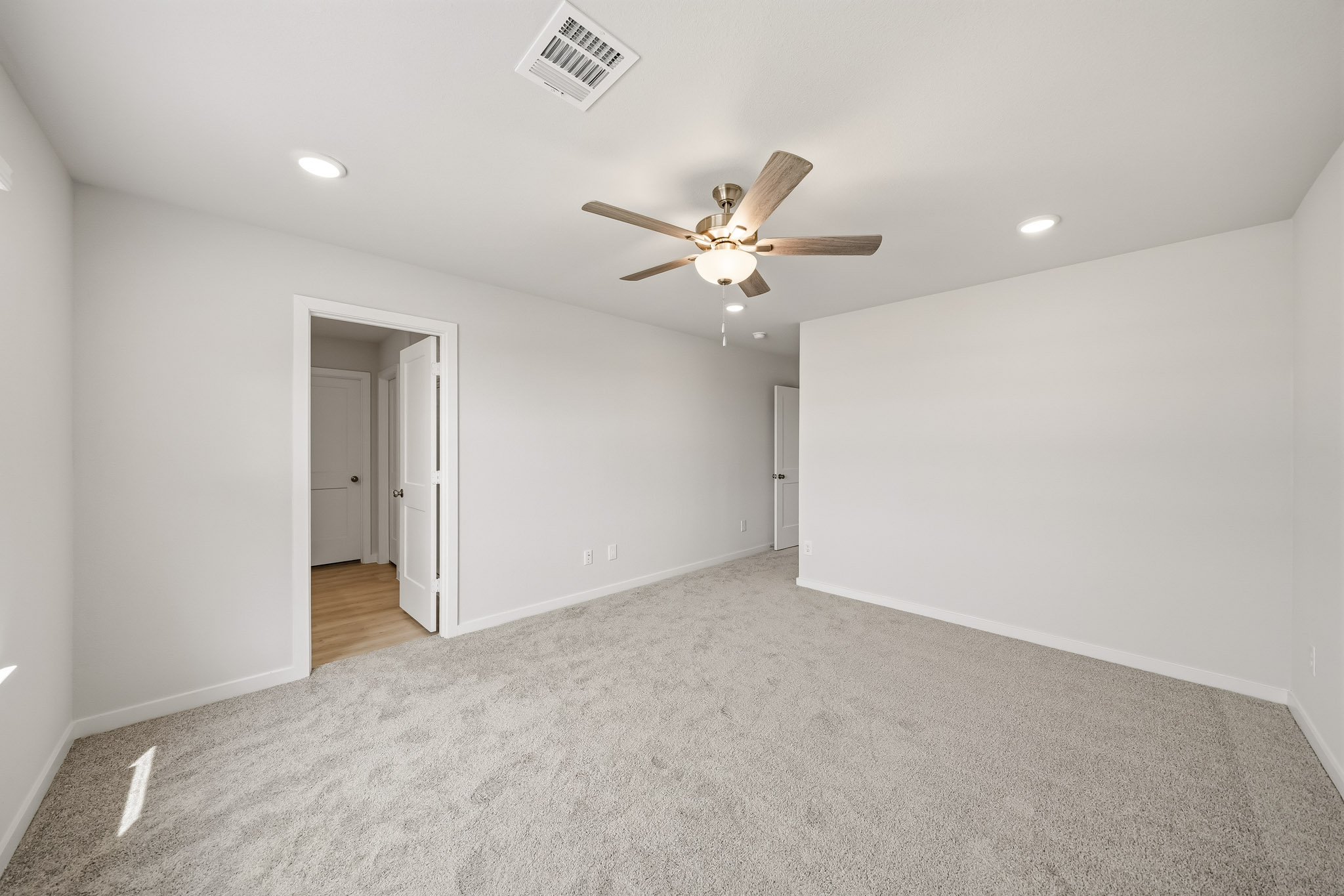 A room with a ceiling fan and a door.