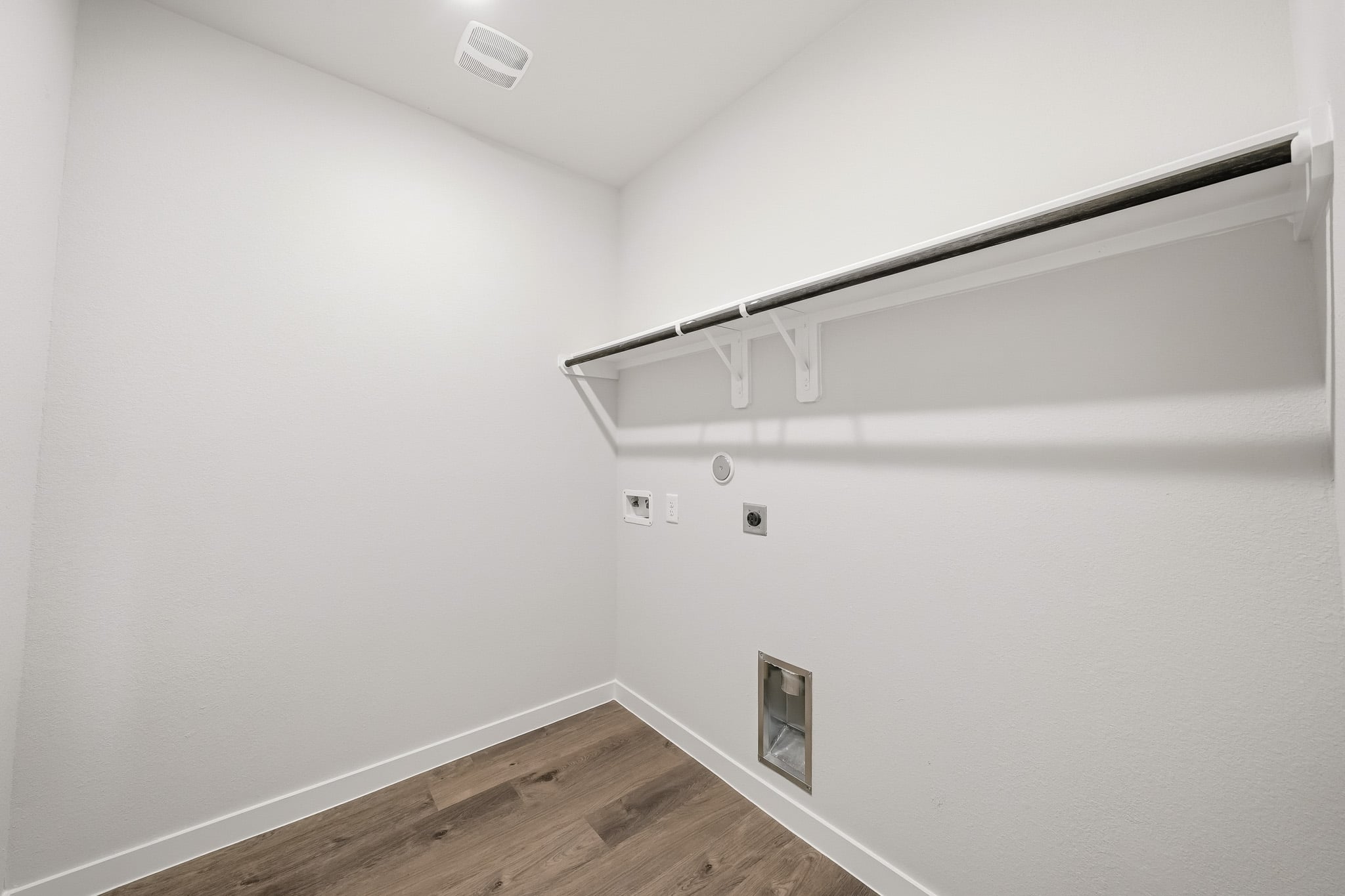 A white wall with a metal bar.