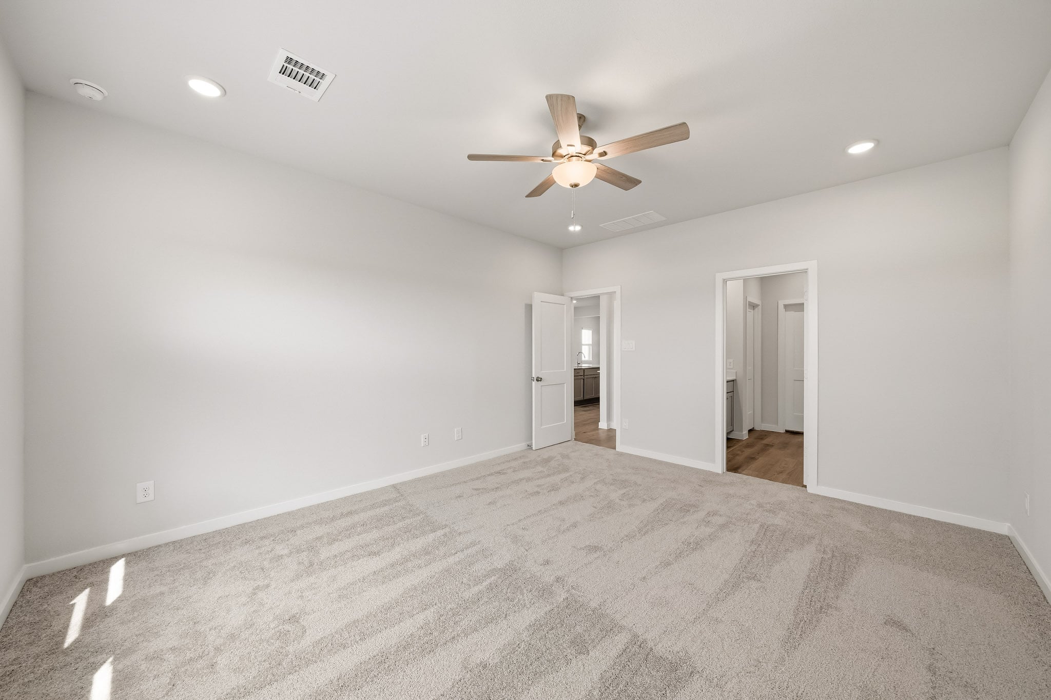 A room with a ceiling fan and a carpet.