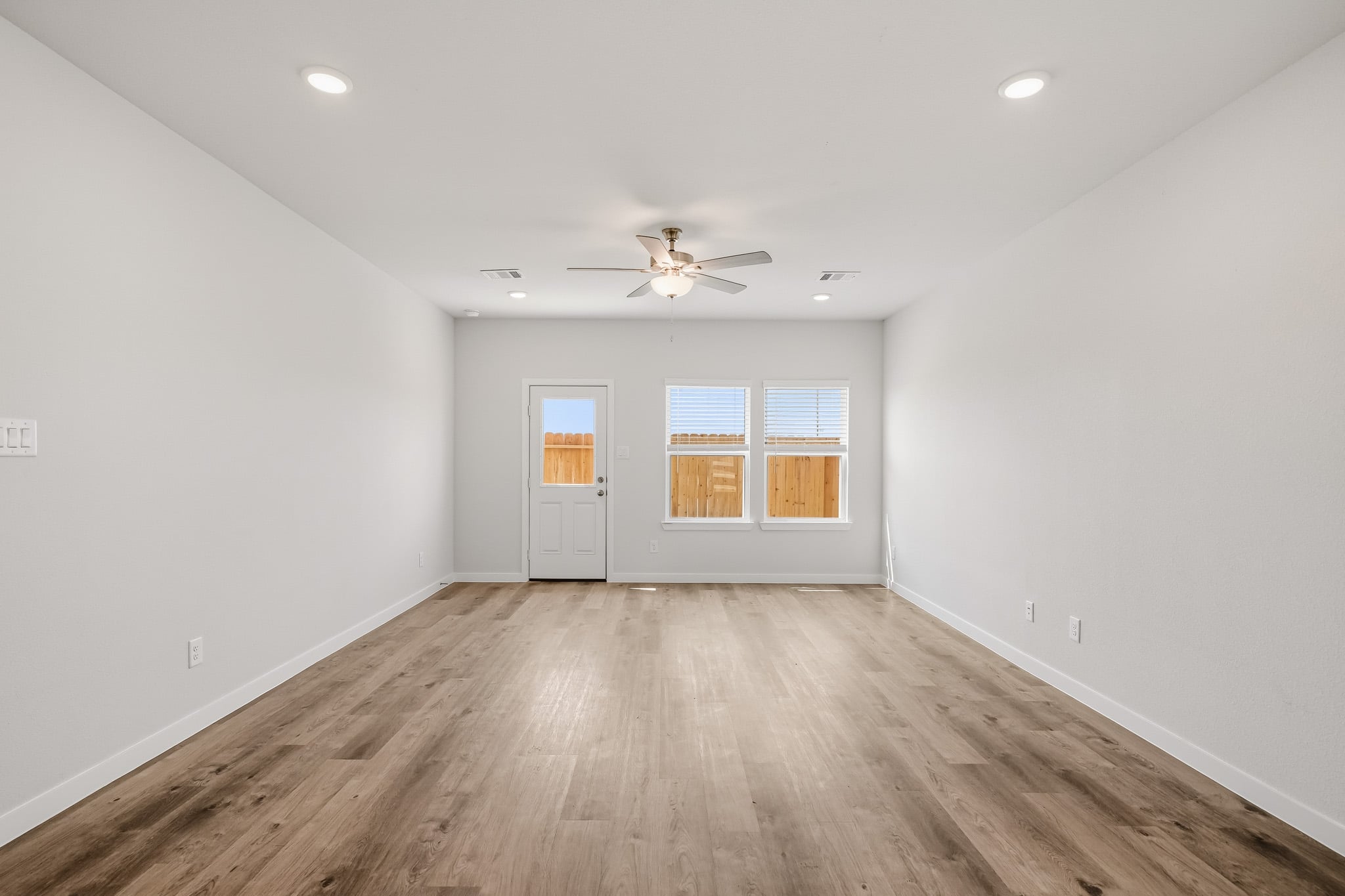 A room with a wood floor and a ceiling fan.