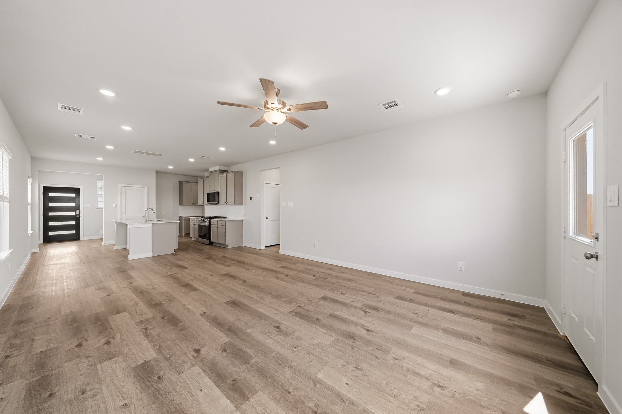 A large empty room with a wood floor and a ceiling fan.