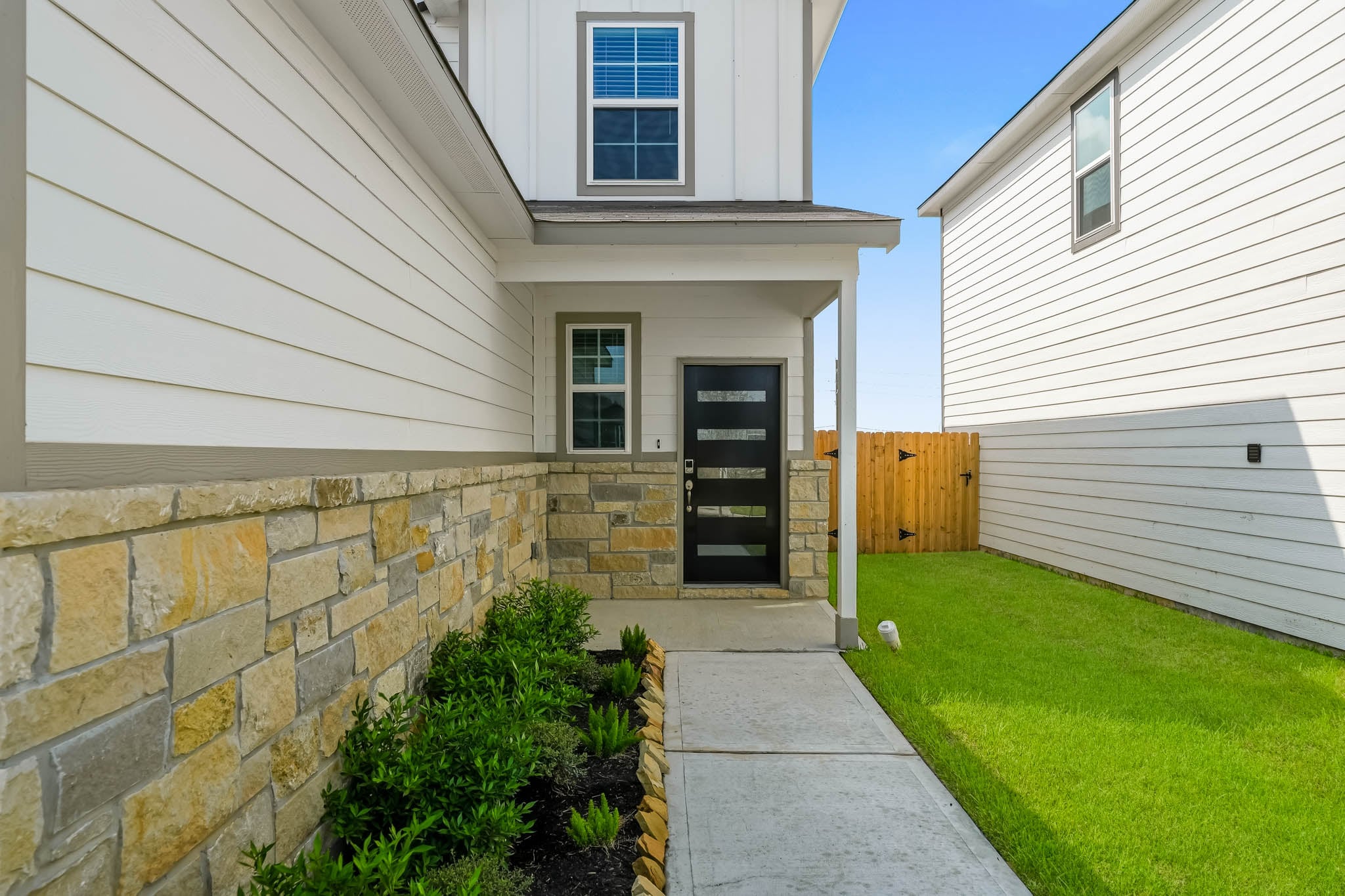 A house with a stone wall and grass.