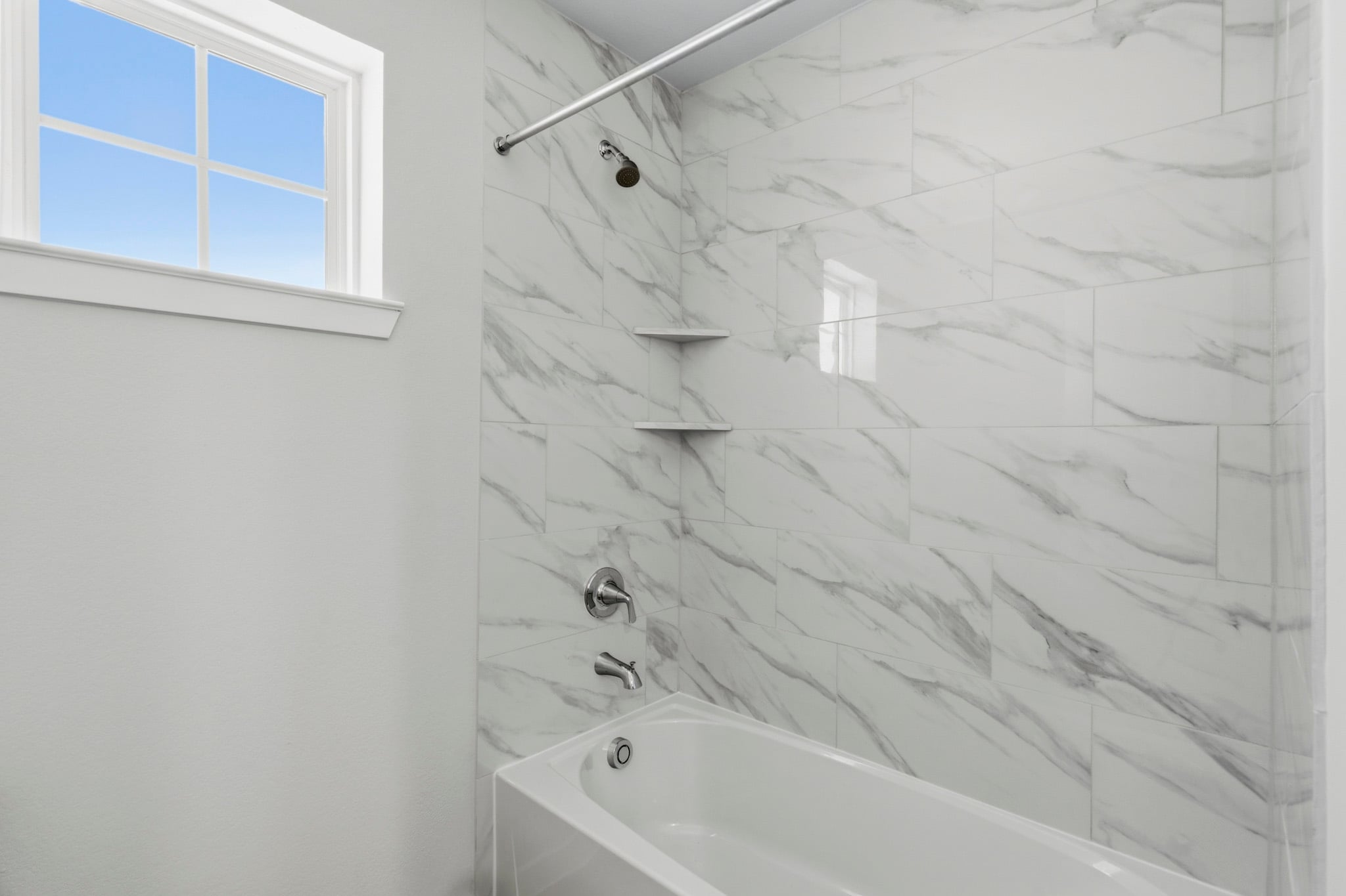 A bathroom with a bathtub and a window.