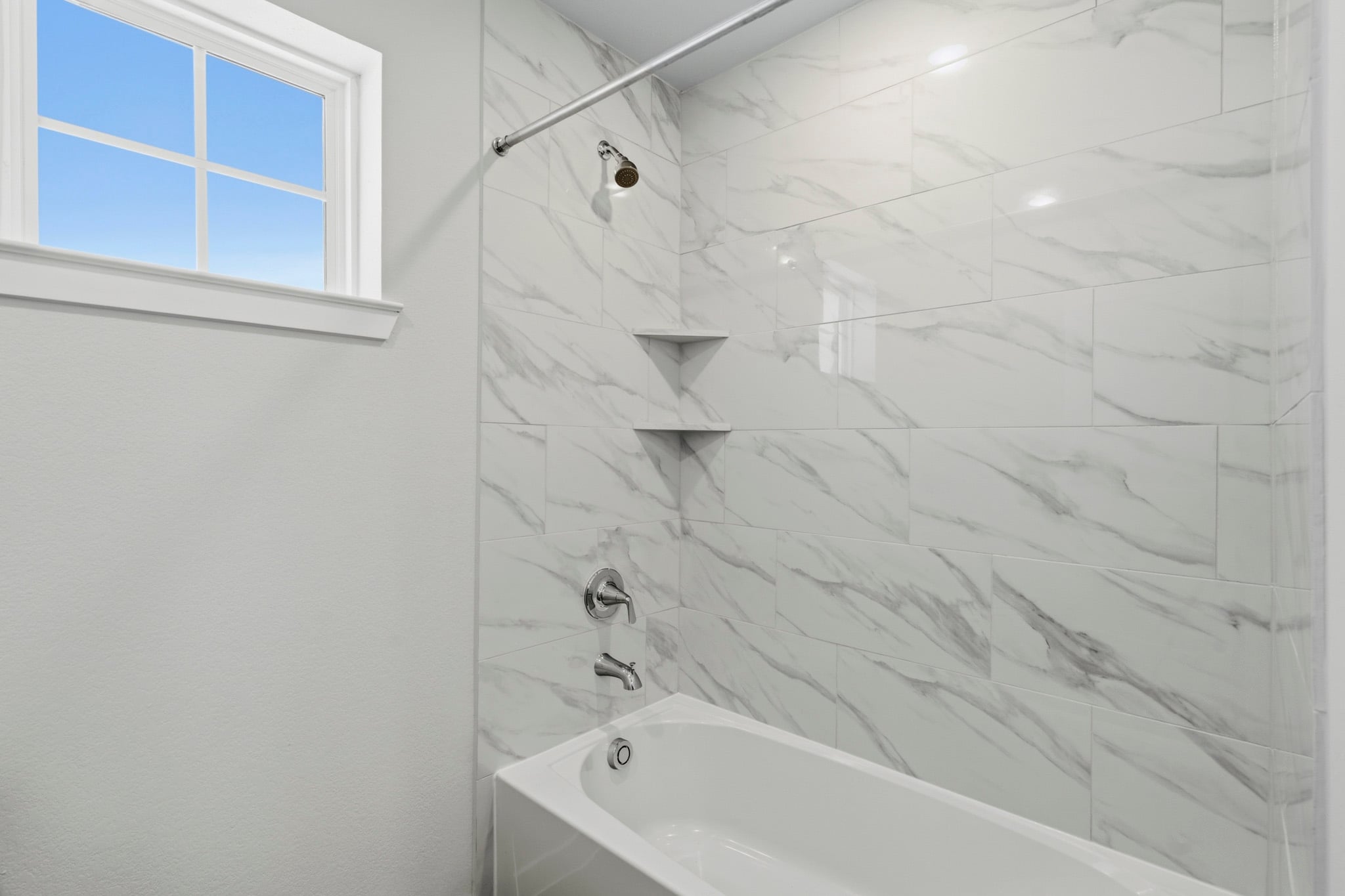 A bathroom with a bathtub and a window.