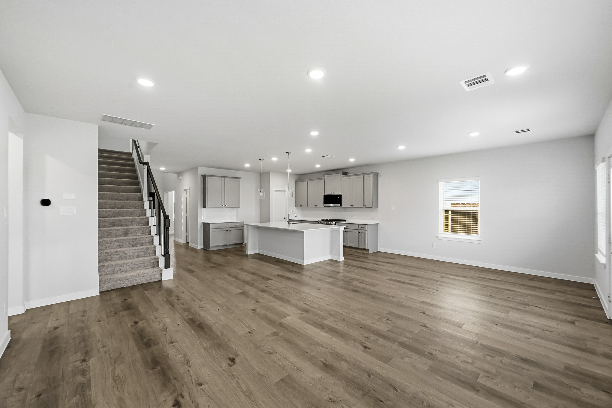 A large empty room with a wood floor and a staircase.