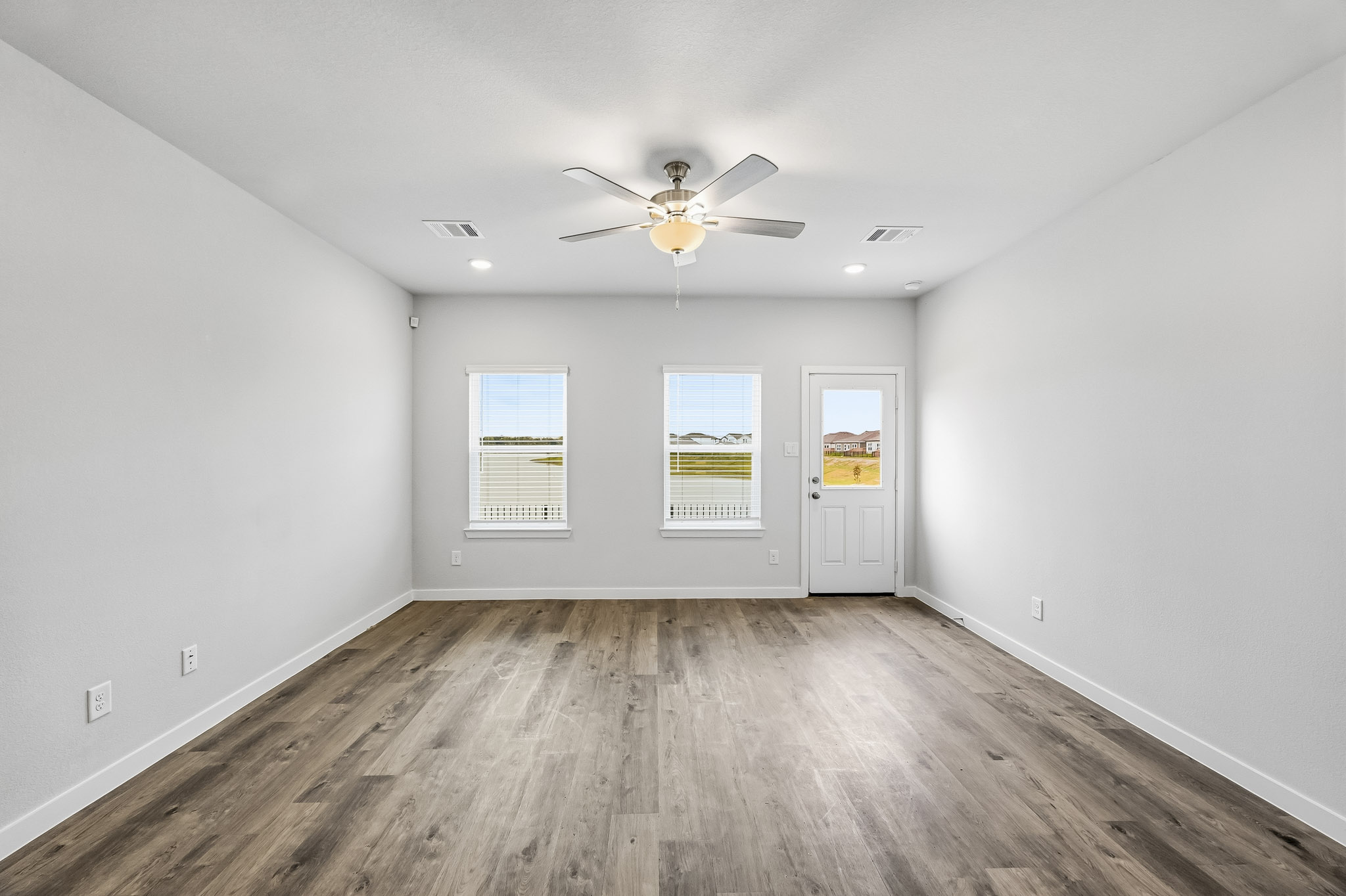 A room with a ceiling fan and a wood floor.