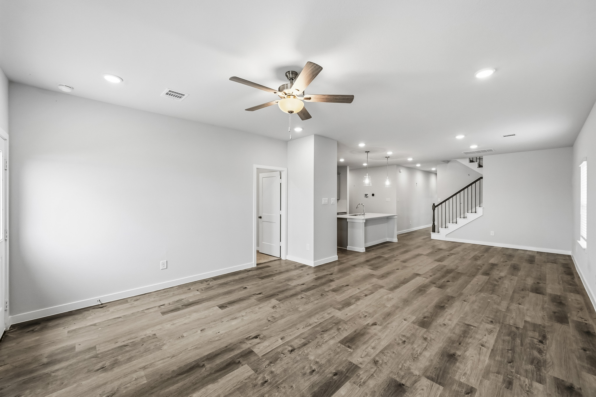 A large empty room with a ceiling fan and wood floors.