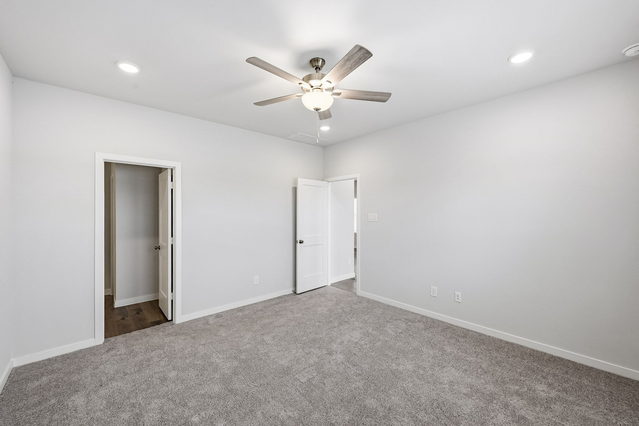 A room with a ceiling fan and a door.