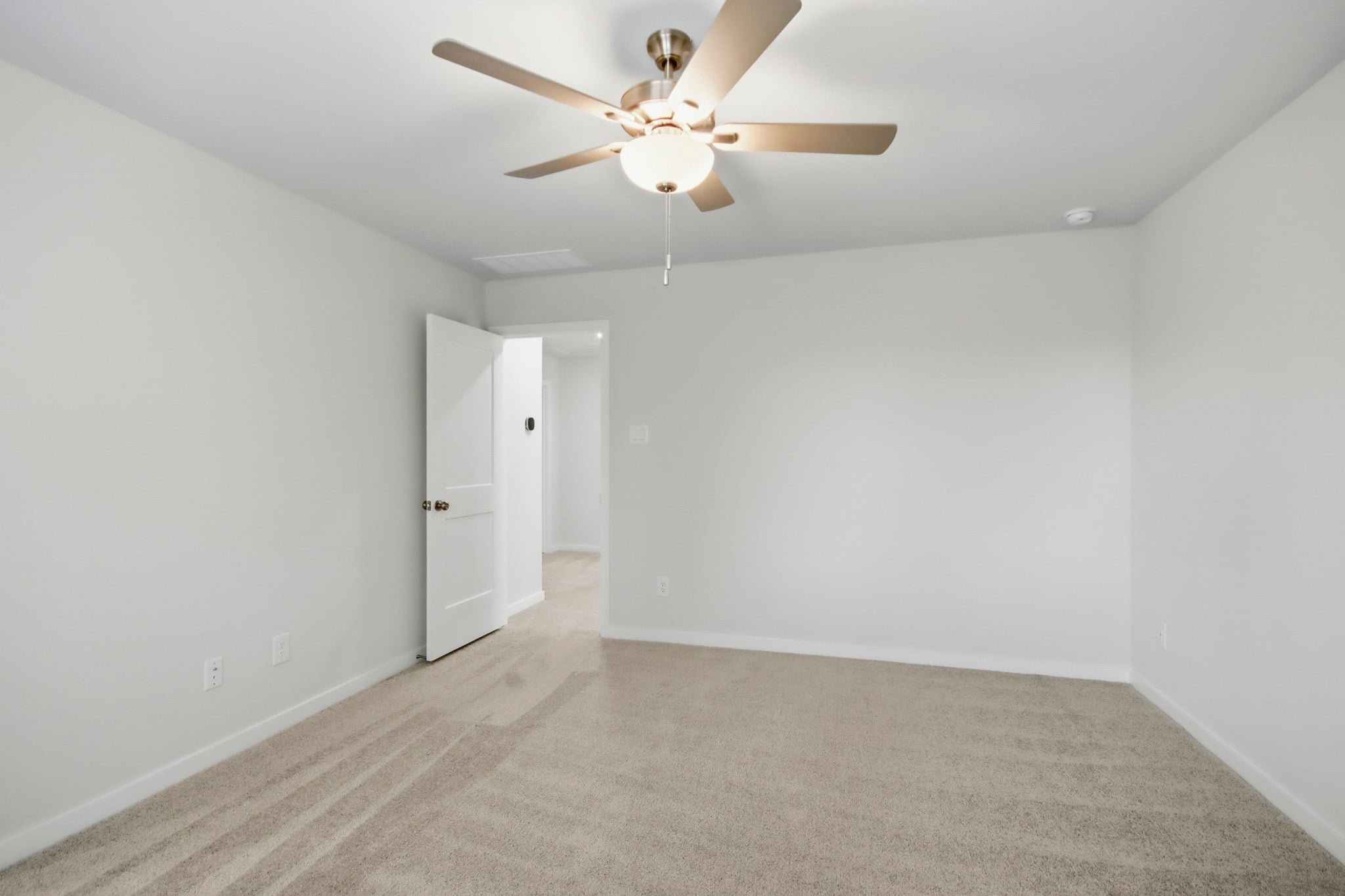A room with a ceiling fan and white walls.