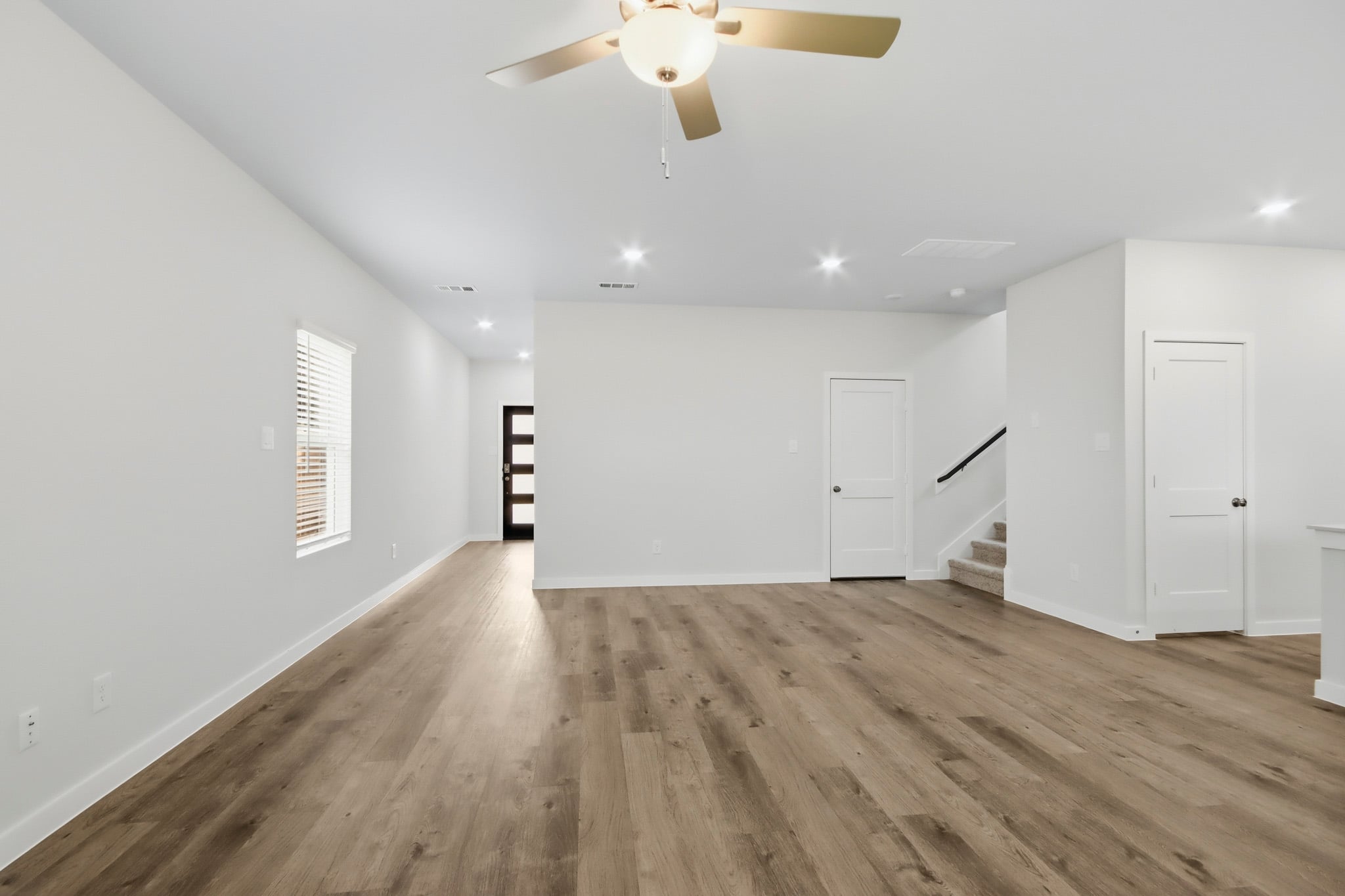 A room with a ceiling fan and white cabinets.