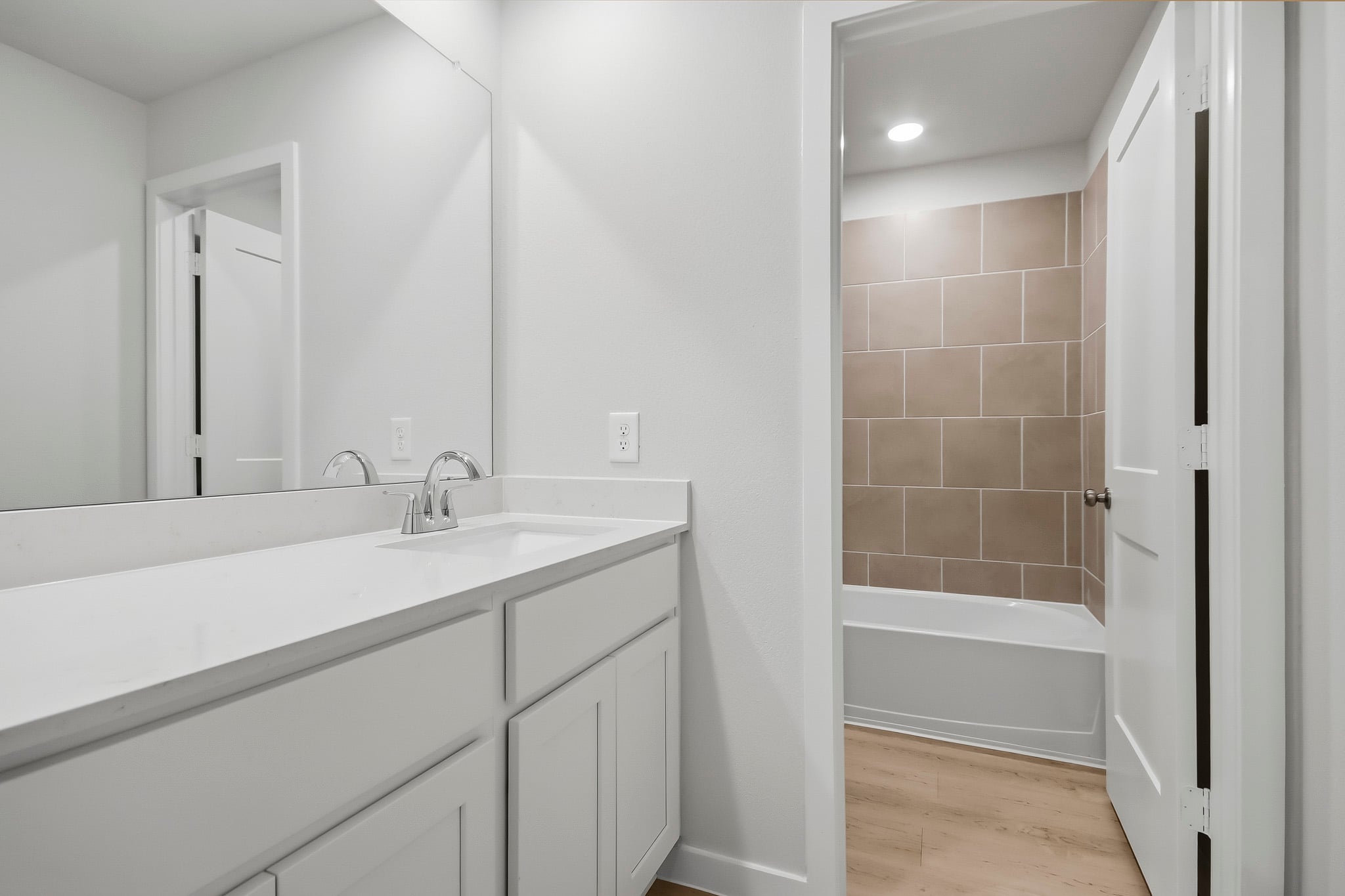 A bathroom with a tub sink and mirror.