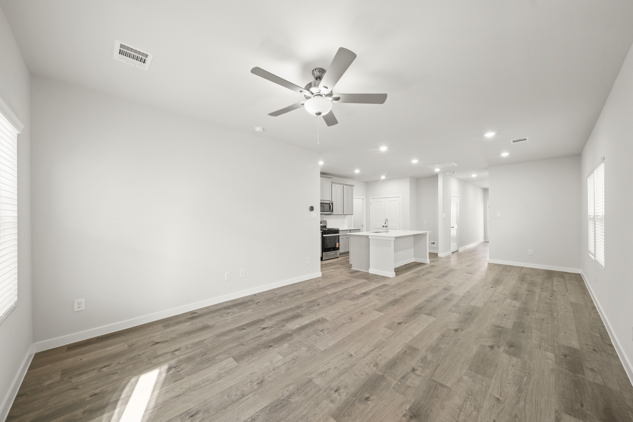 A room with a ceiling fan and a wood floor.