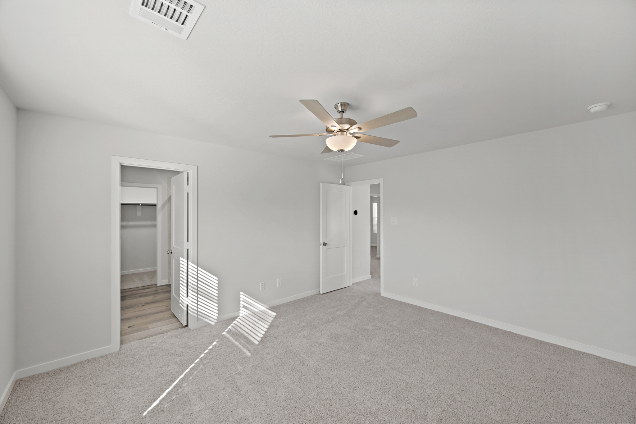 A room with a ceiling fan and a door.