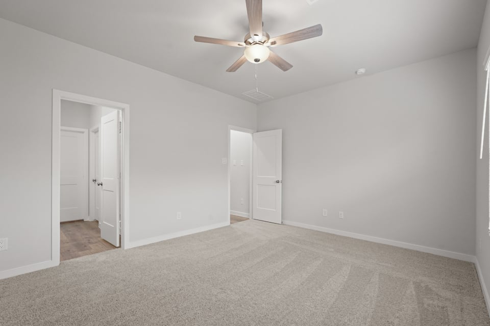 A room with a ceiling fan and white doors.