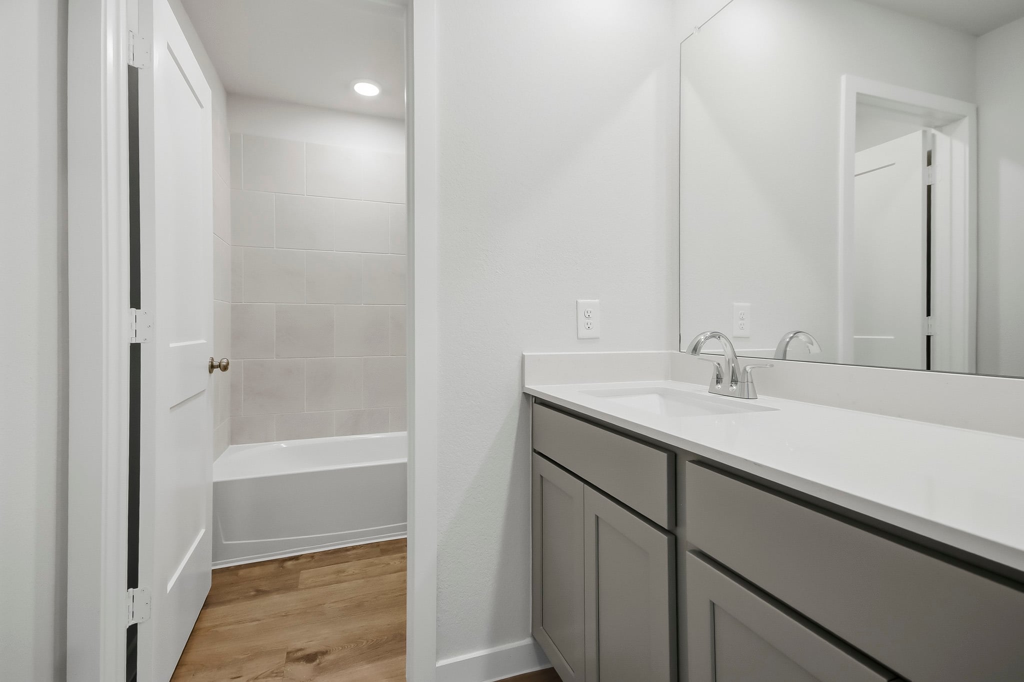 A bathroom with a tub sink and cabinets.
