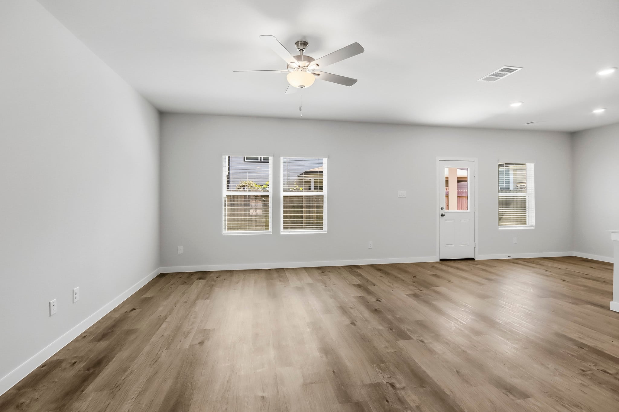 A room with a ceiling fan and a wood floor.