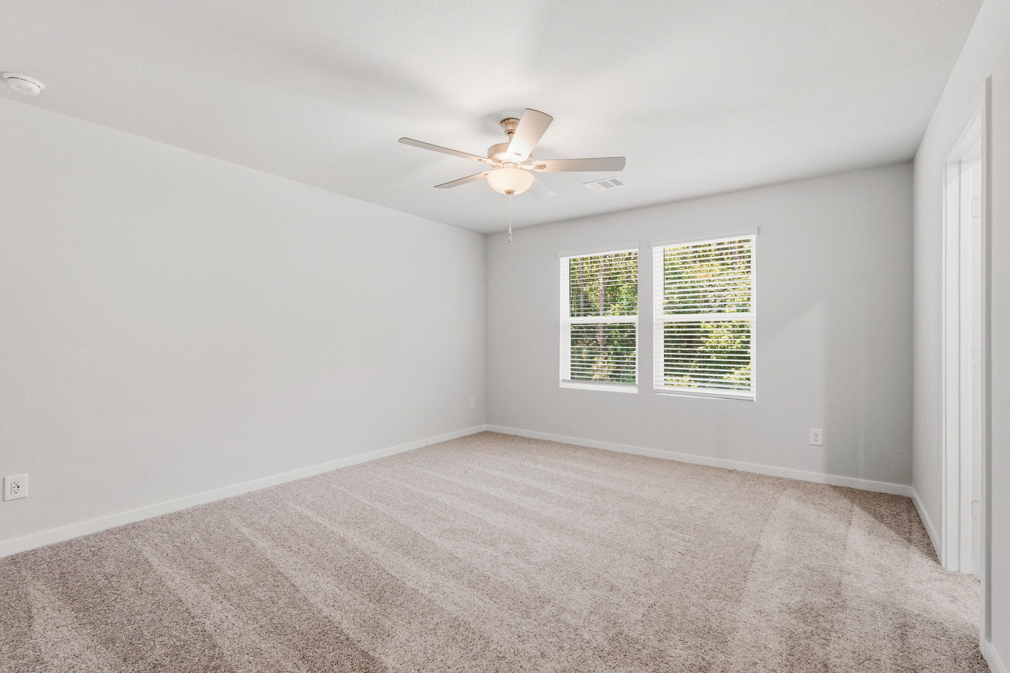 A room with a ceiling fan and a carpet.