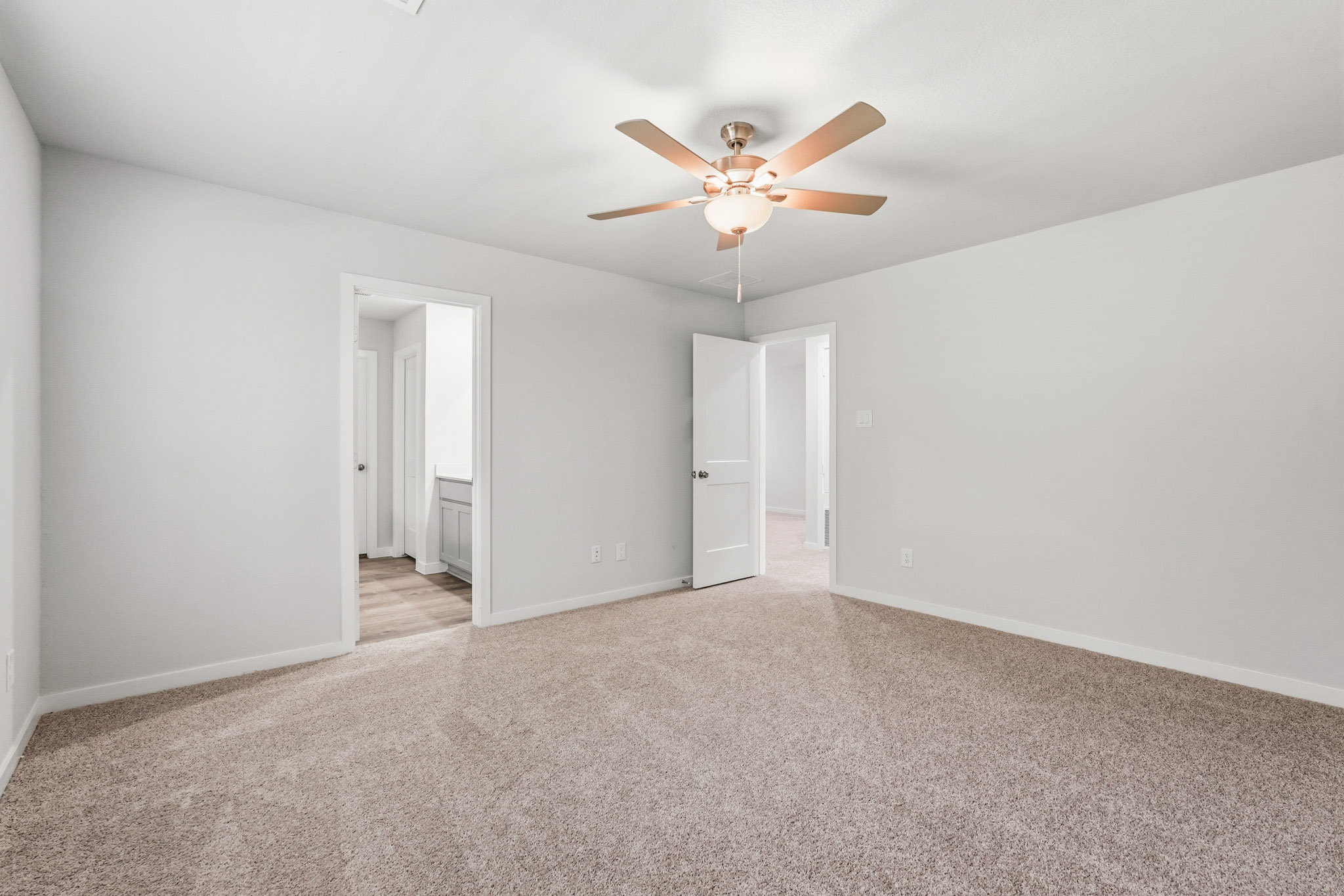 A room with a ceiling fan and white walls.