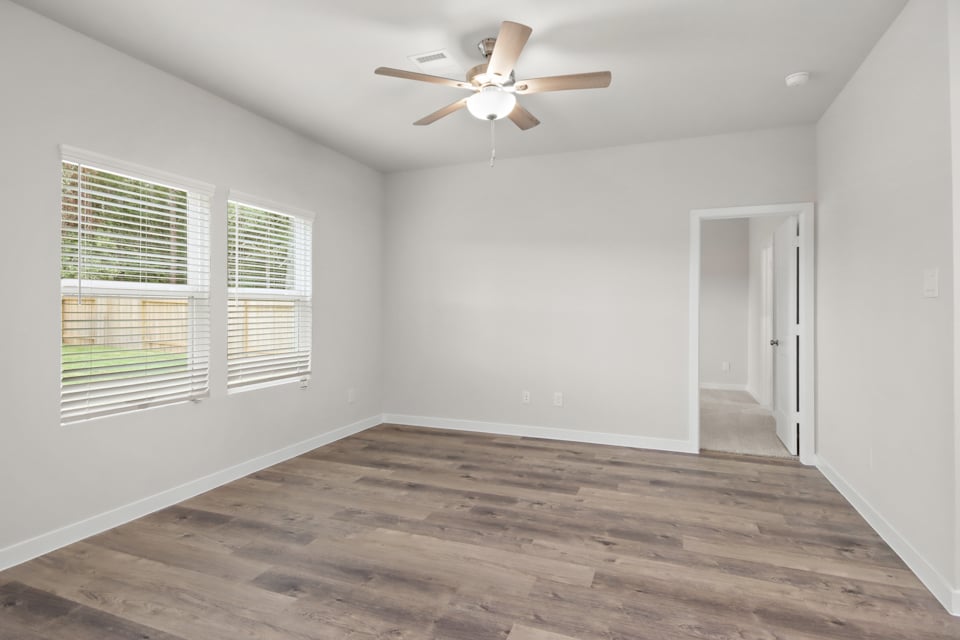 A room with a ceiling fan and a wood floor.