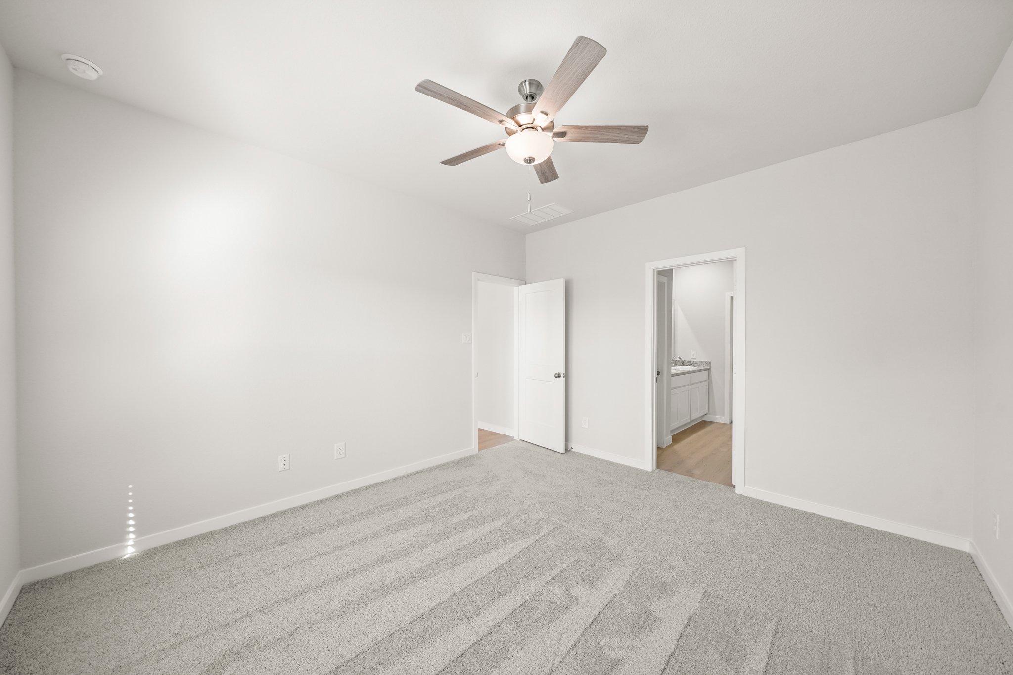 A room with a ceiling fan and a door.