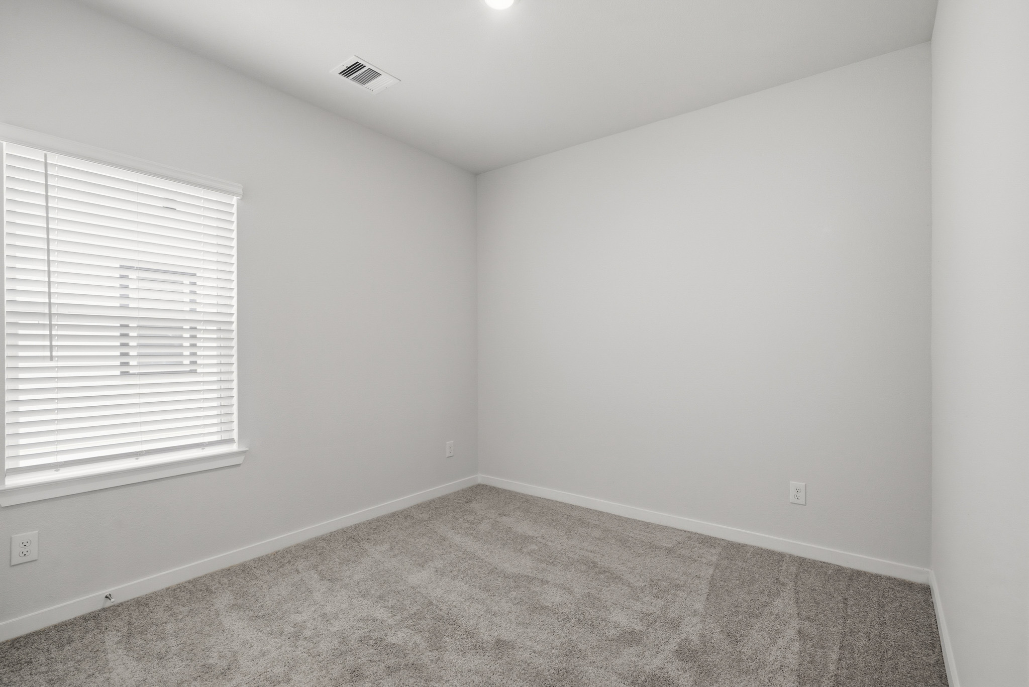 A room with a carpet and a window.