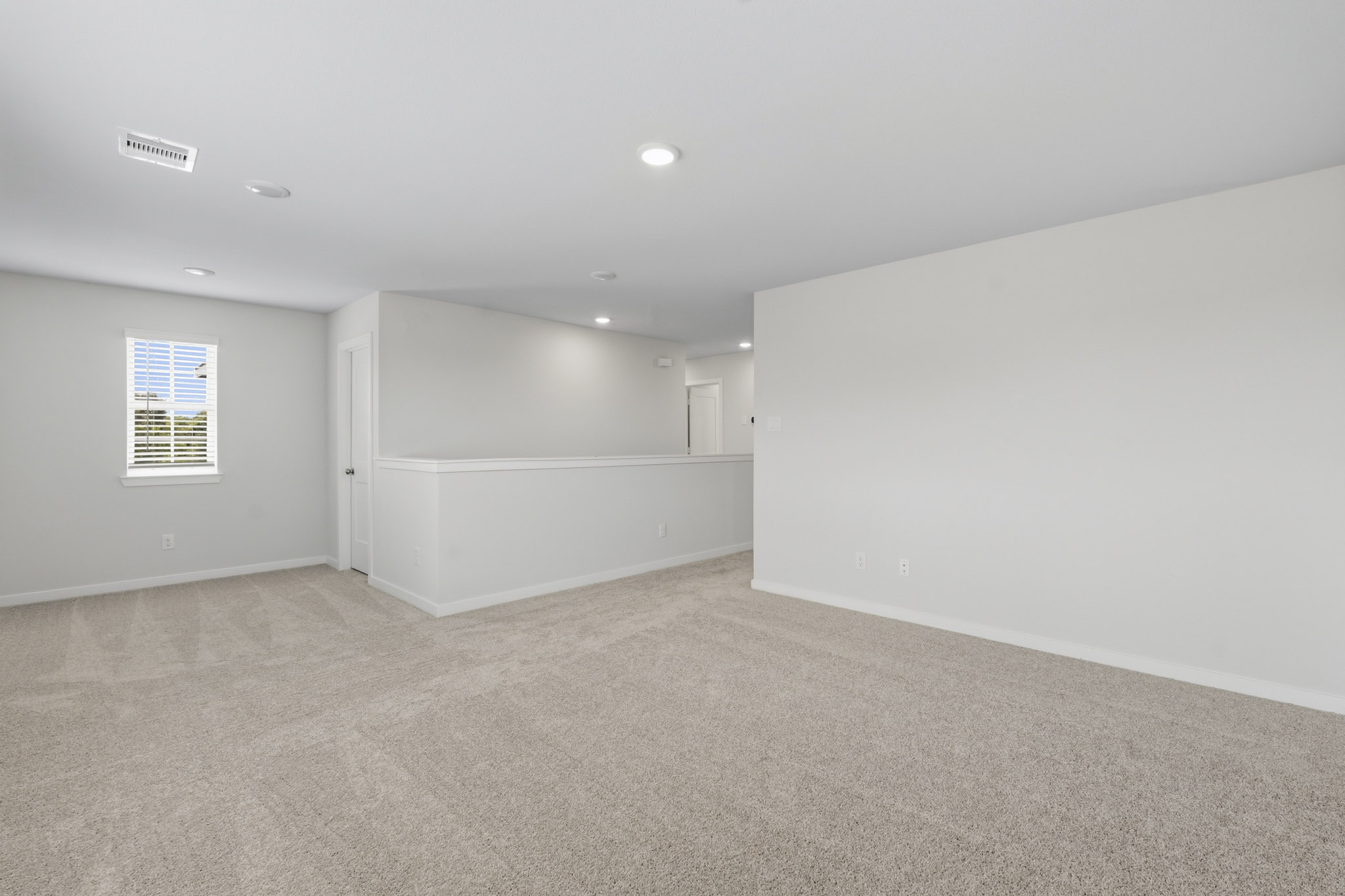 A room with a carpet and a white wall.