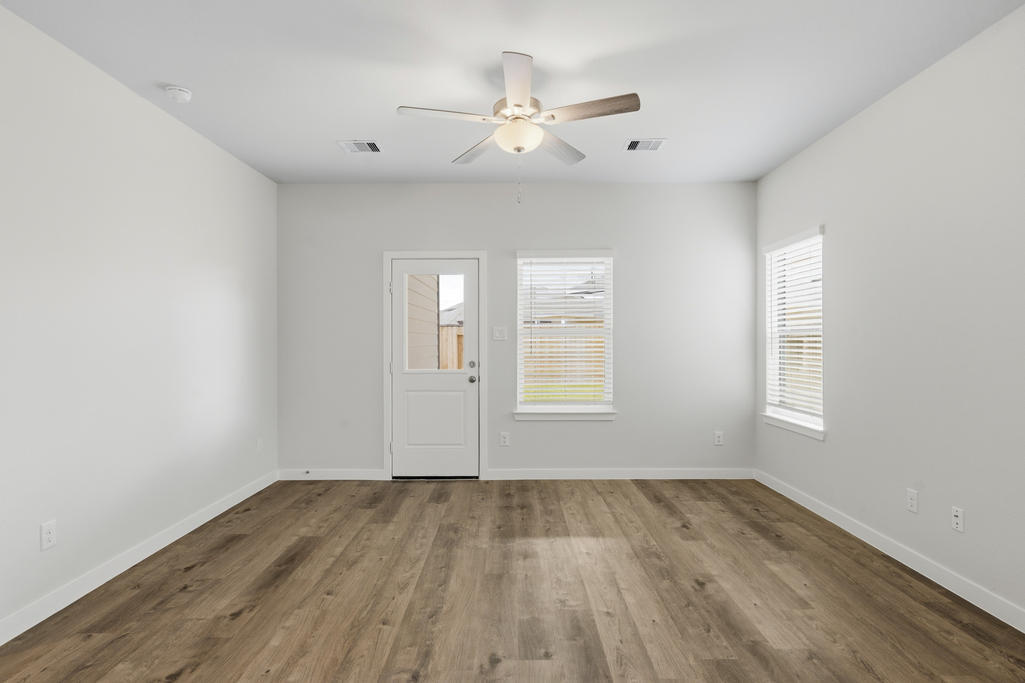 A room with a ceiling fan and a wood floor.