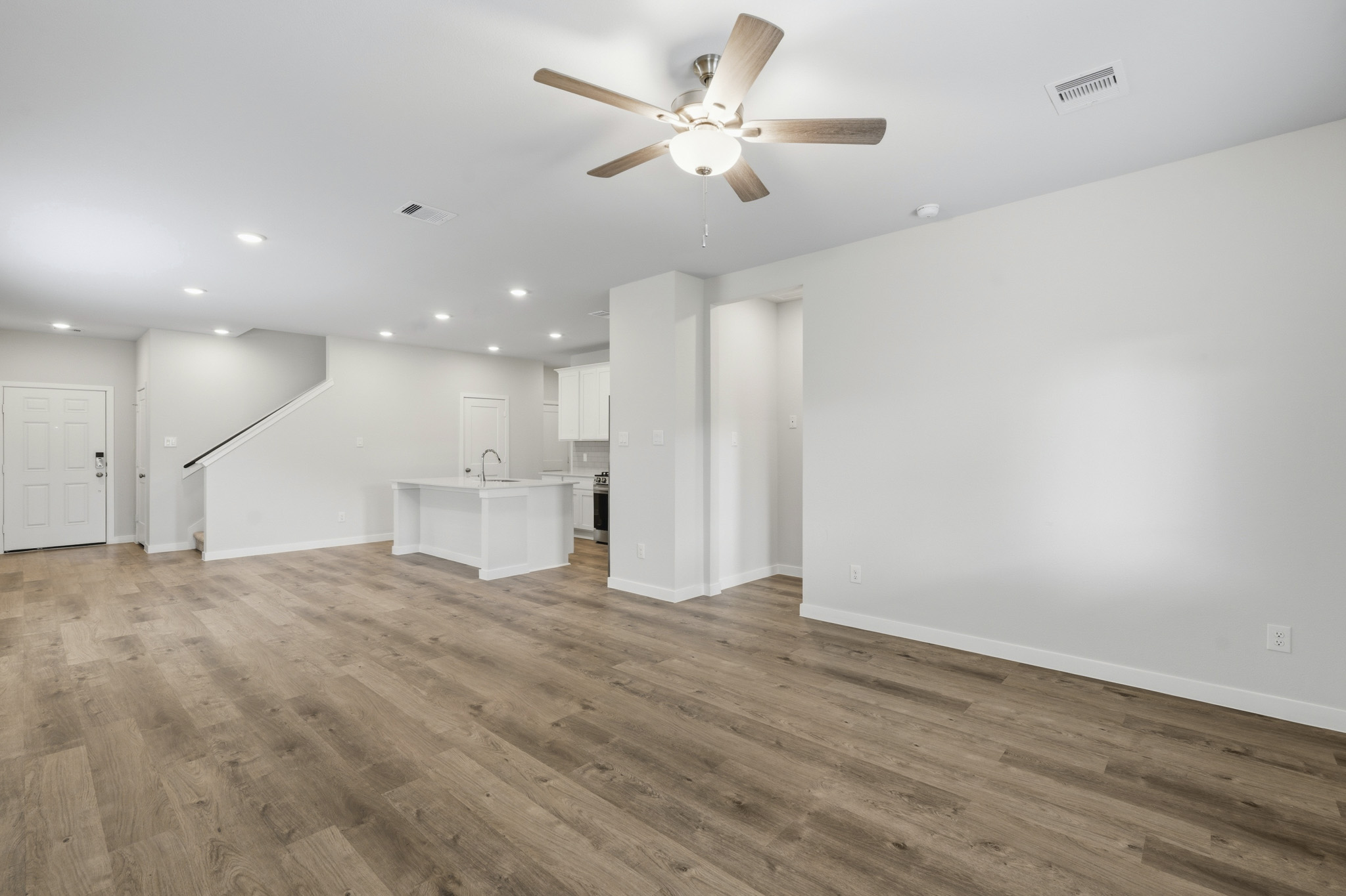 A room with a ceiling fan and a wood floor.