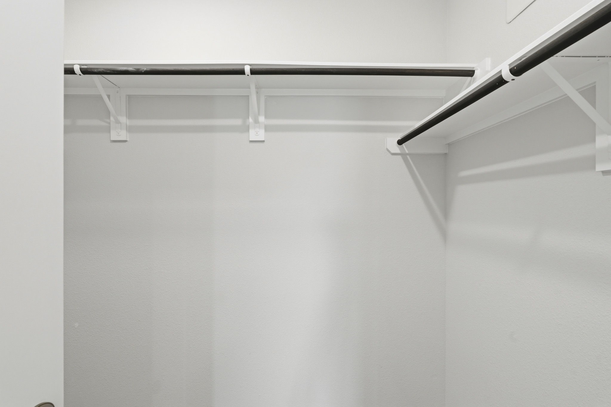 A white wall with a metal bar.
