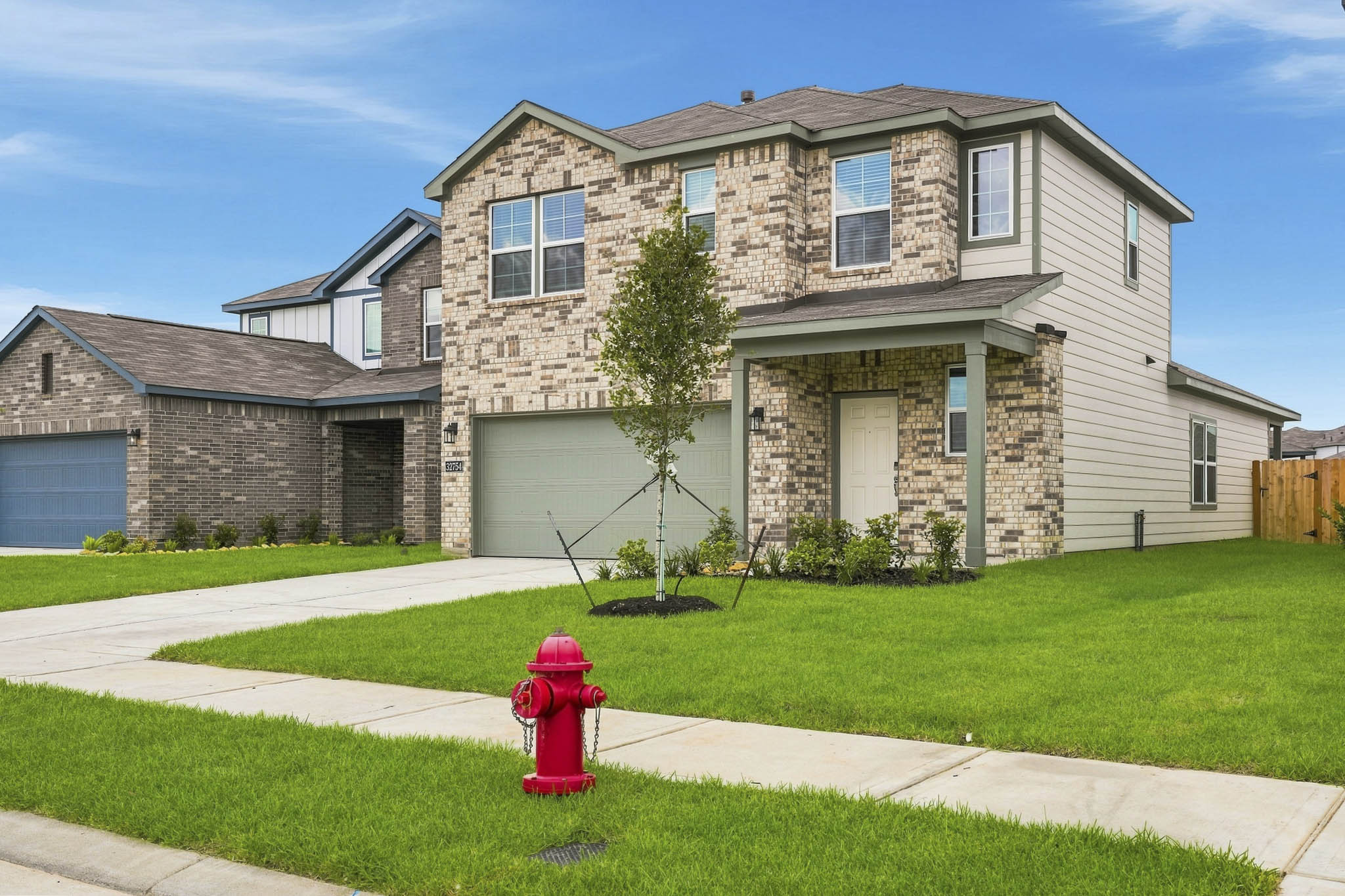 A red fire hydrant in front of a house.