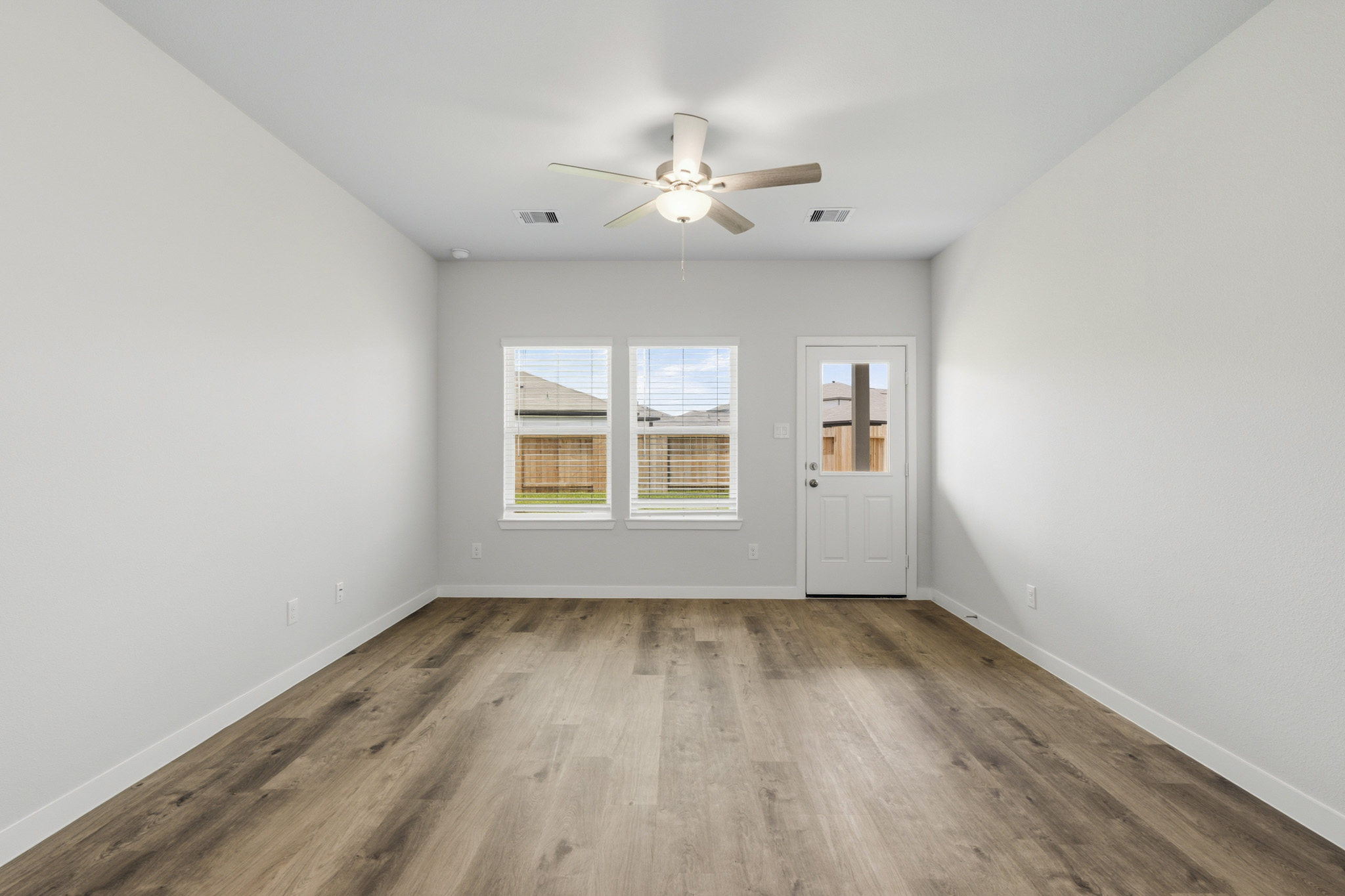 A room with a ceiling fan and a wood floor.
