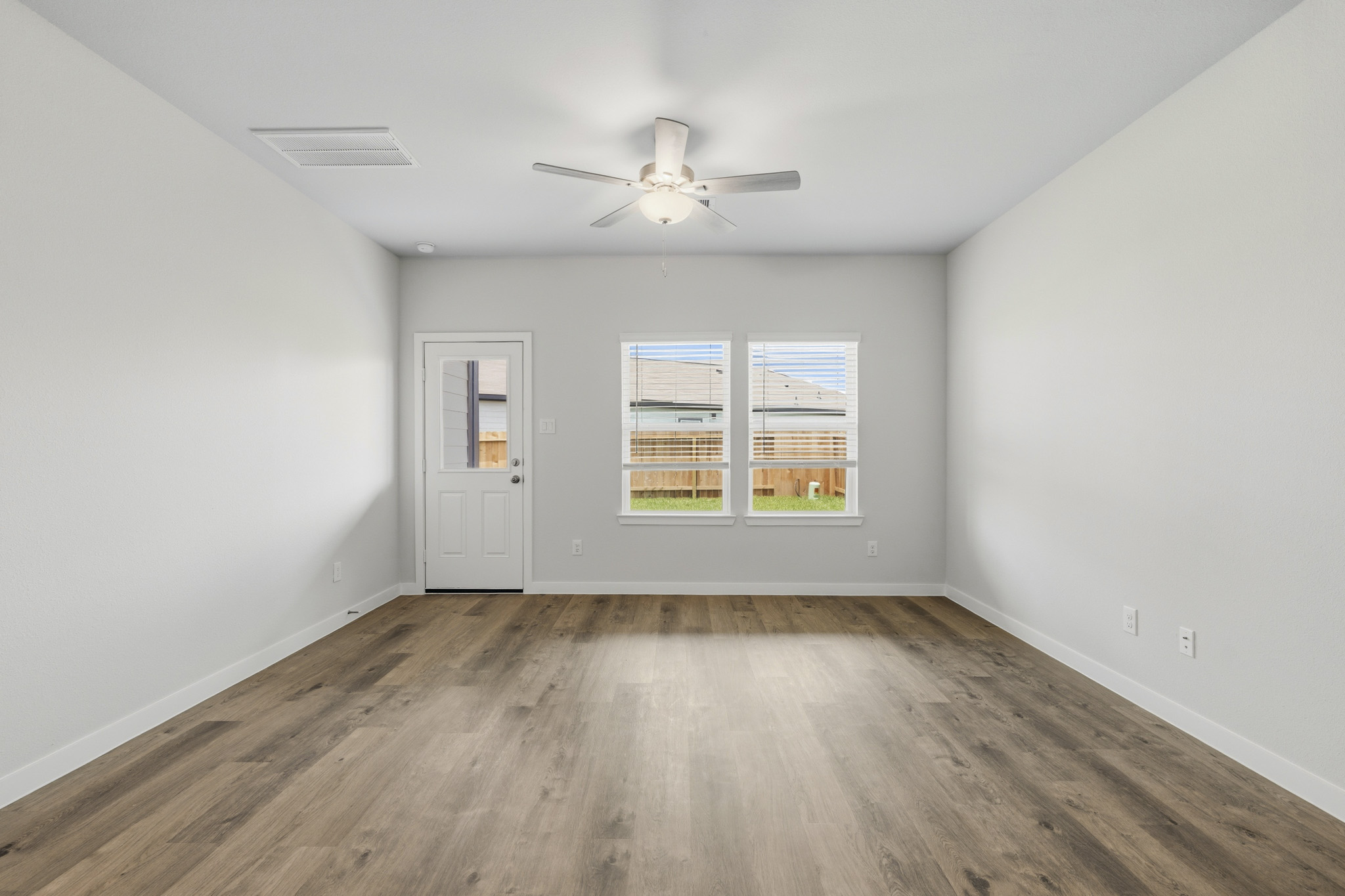 A room with a ceiling fan and a wood floor.