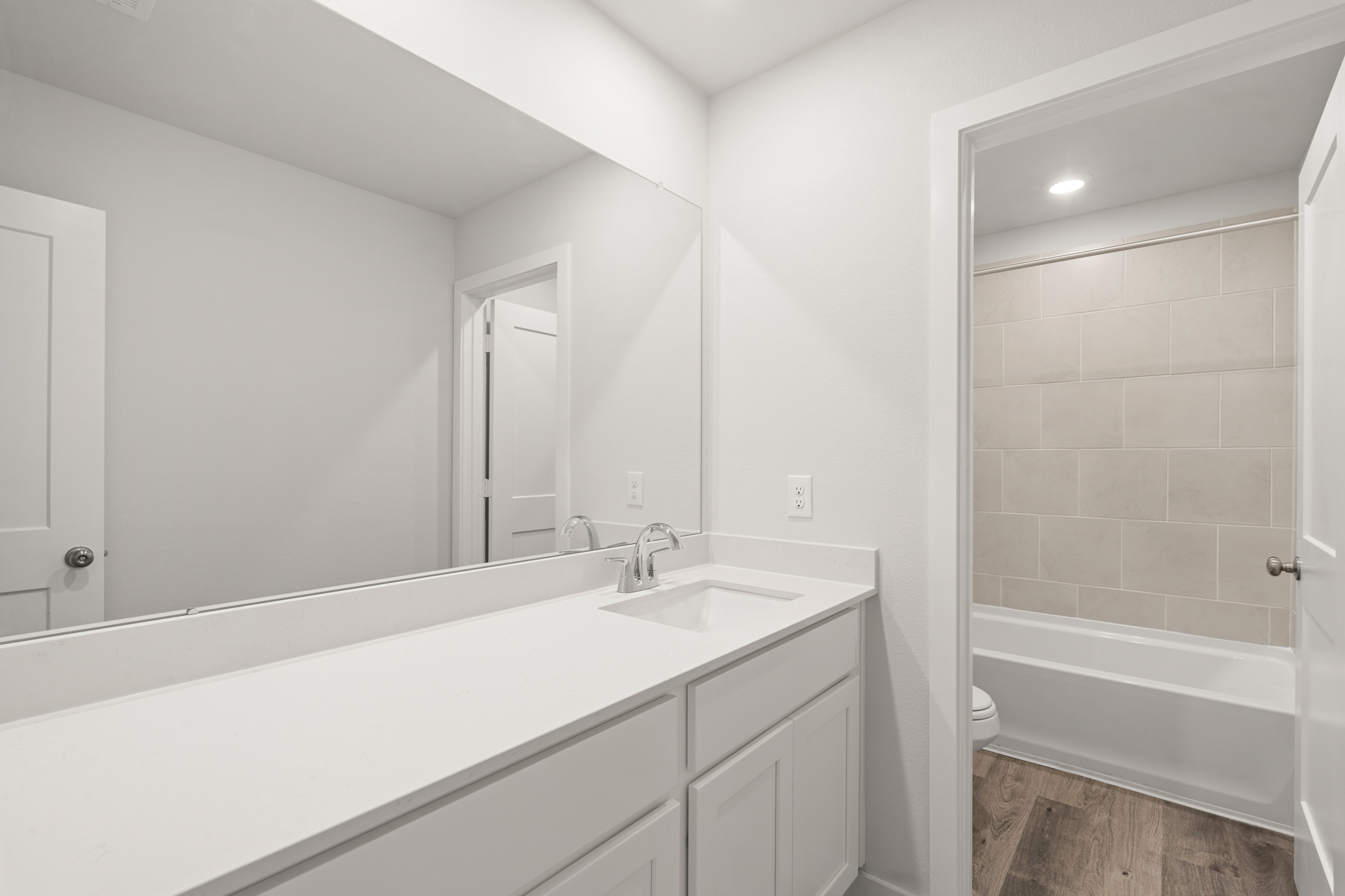 A bathroom with a tub sink and a mirror.