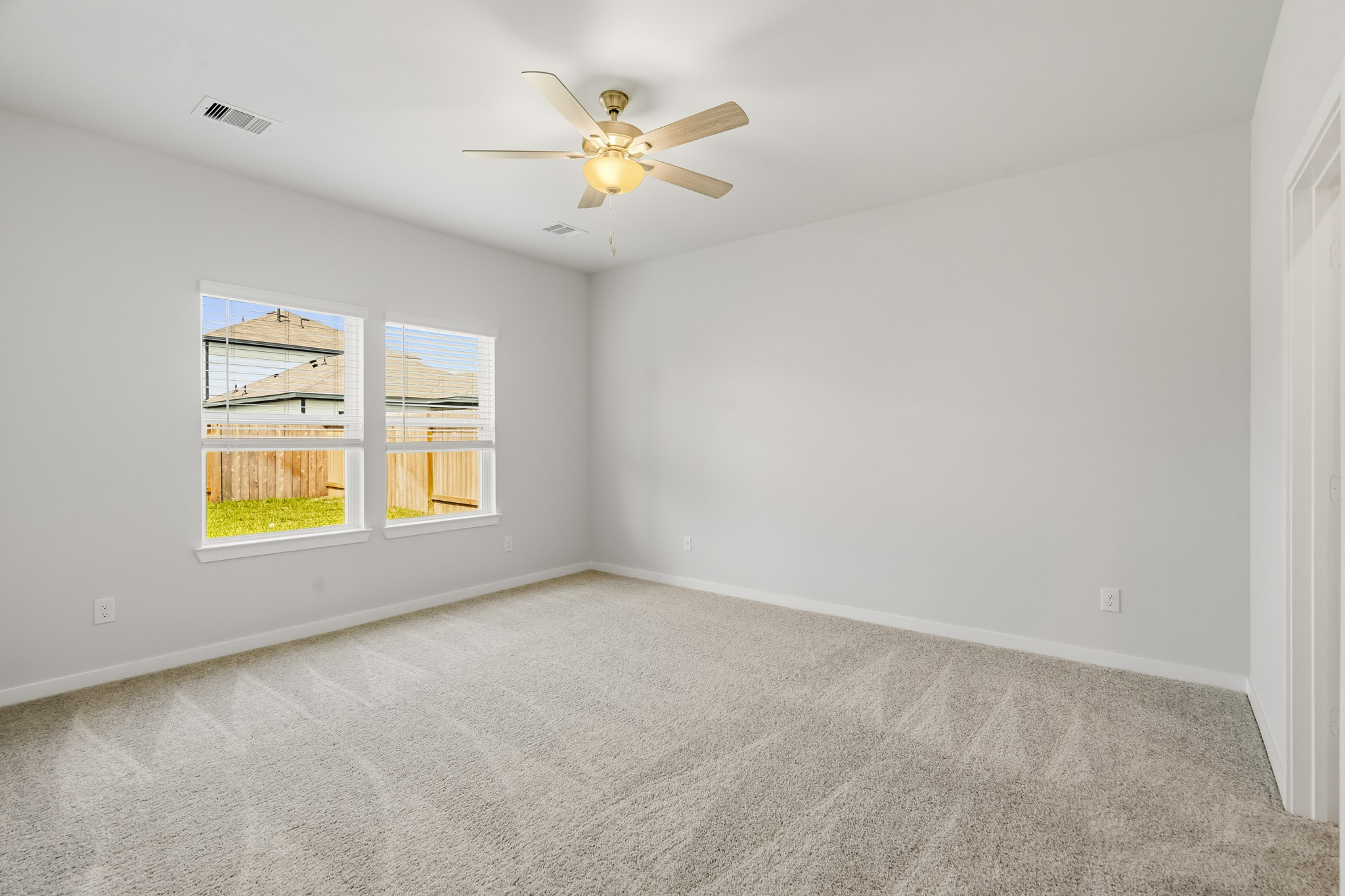 A room with a ceiling fan and a window with a view of the city.