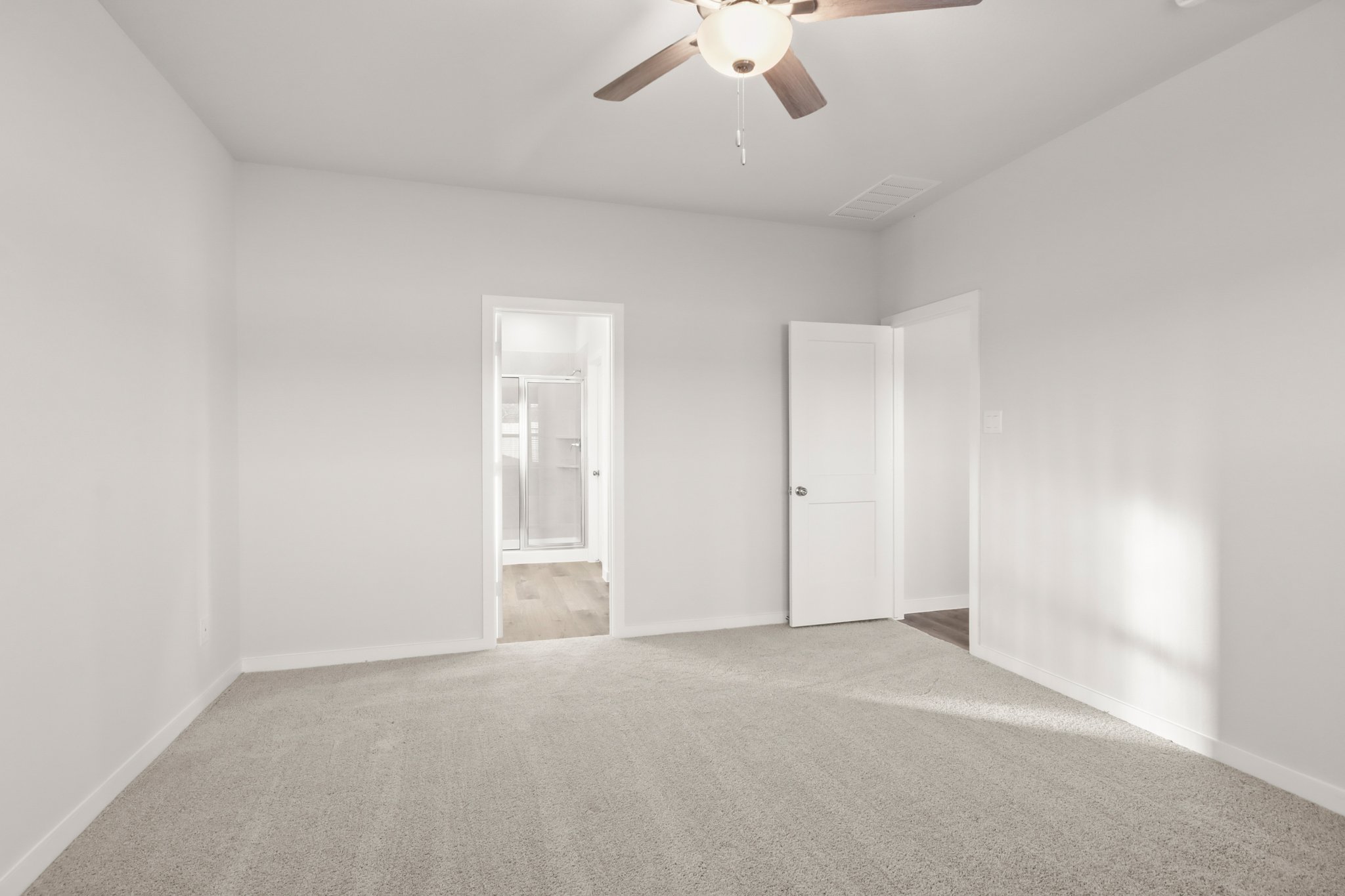 A room with a ceiling fan and a carpet.