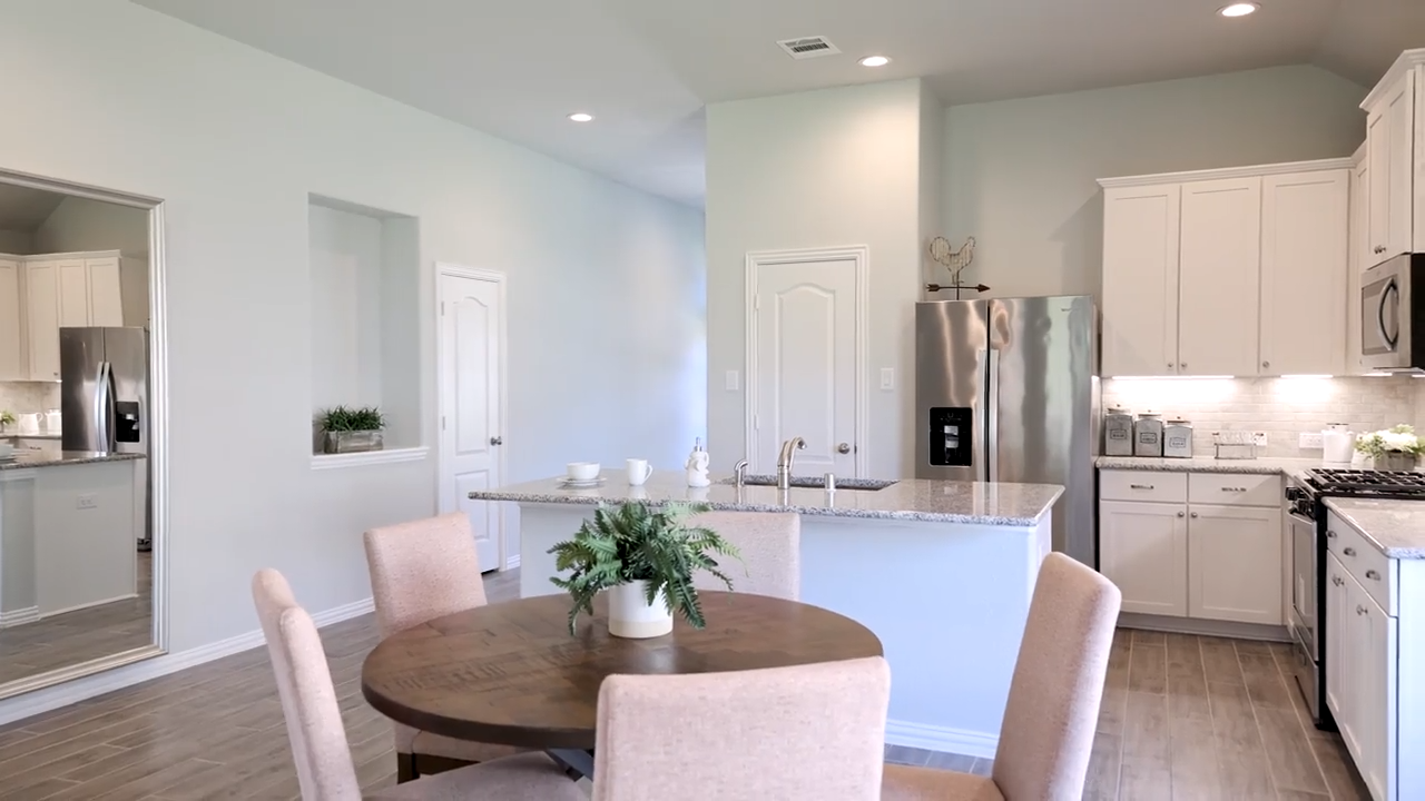 A kitchen with a dining table and white cabinets.