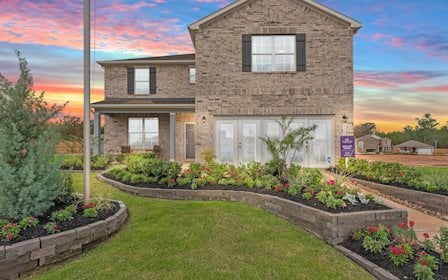 A brick building with a garden in front of it.