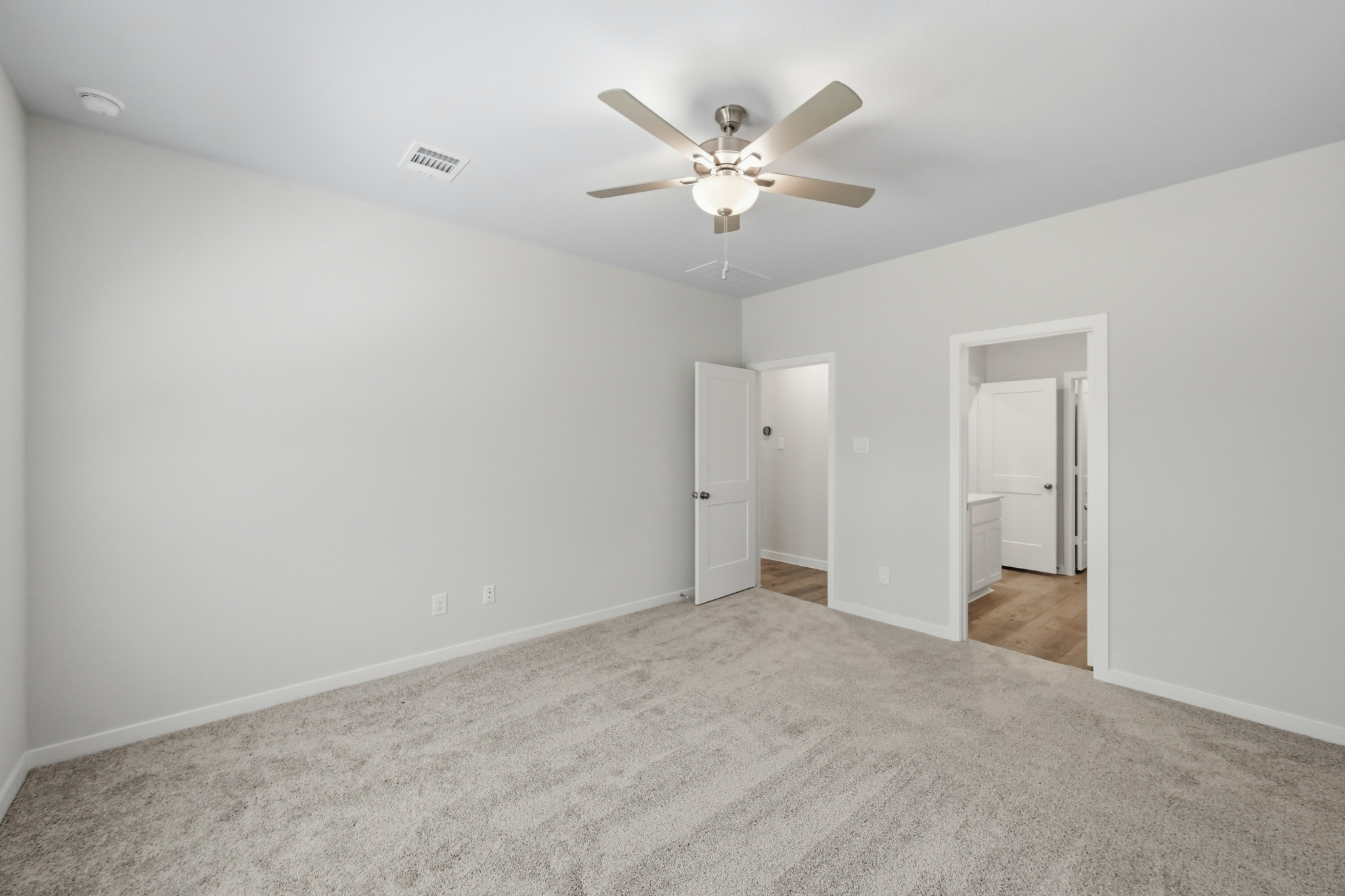 A room with a ceiling fan and a door.