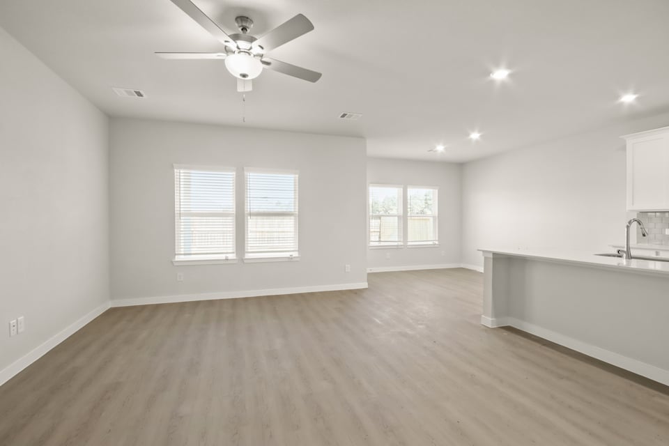 A large empty room with a ceiling fan and a wood floor.
