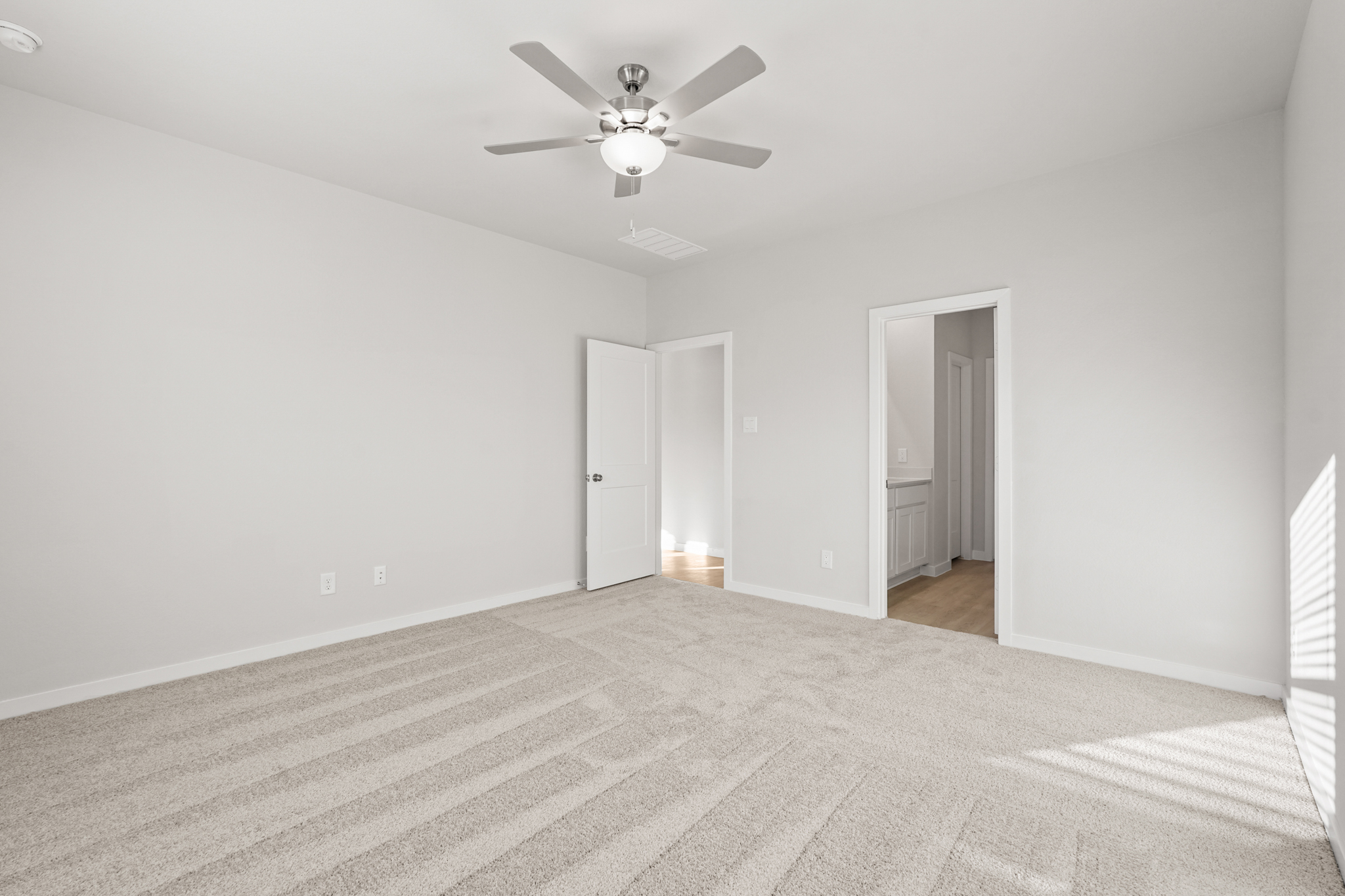A room with a ceiling fan and a carpet.