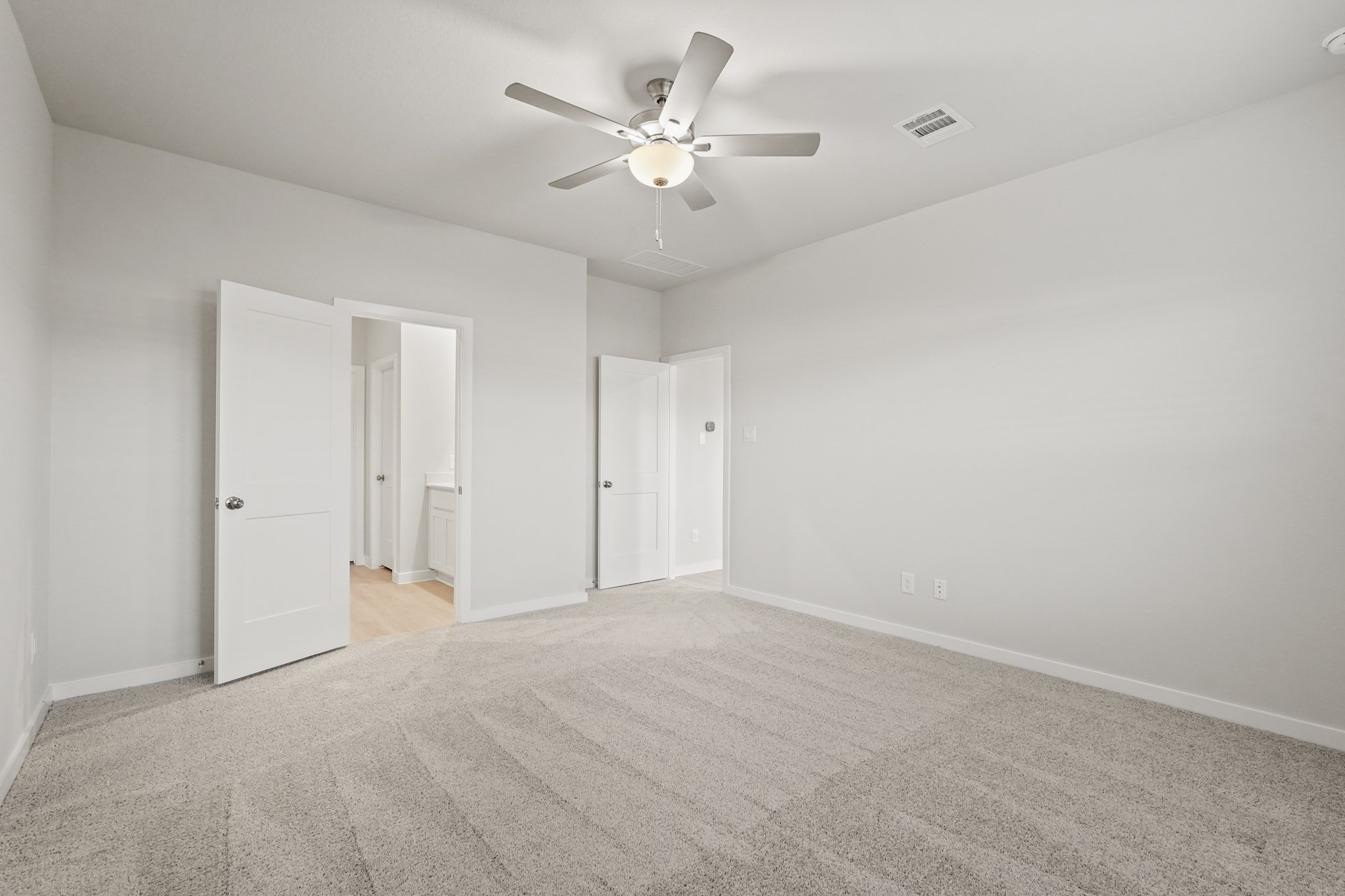 A room with a ceiling fan and white doors.